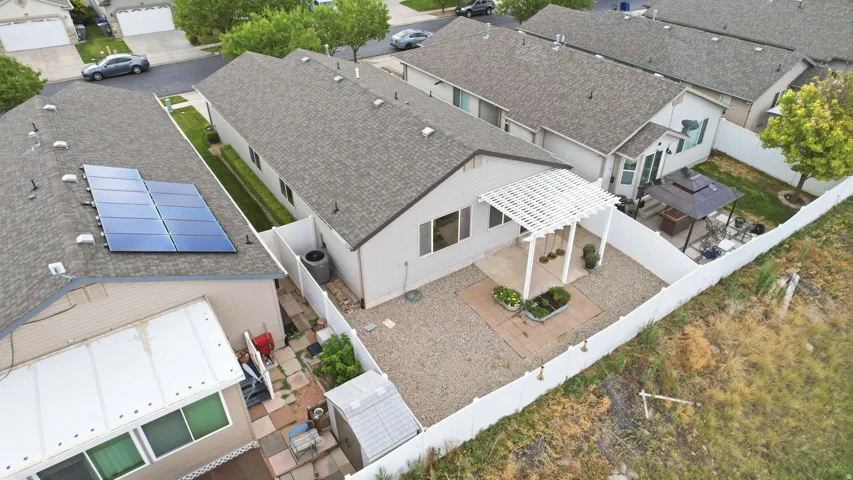 Low-maintenance backyard featuring a white lattice pergola, gravel patio area, privacy fencing, and a separate paved side yard