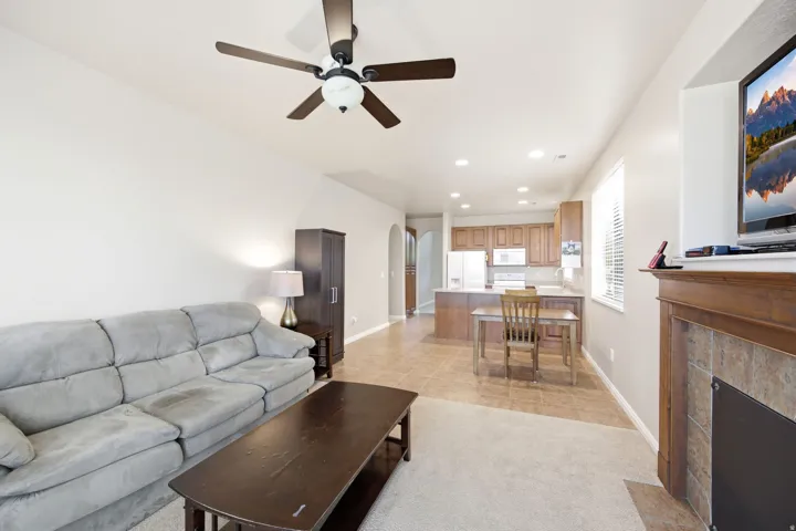 Living area featuring a fireplace with a wood-finish mantel and tile surround, accompanied by an overhead ceiling fan