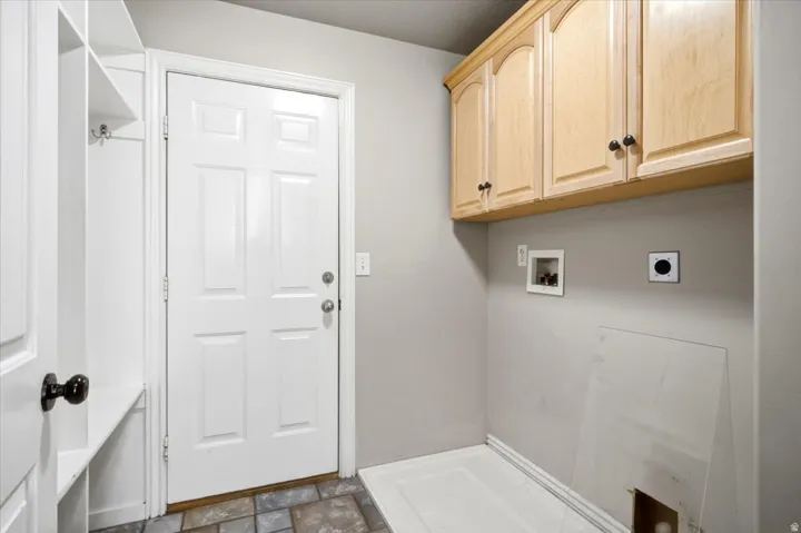 Utility room featuring built-in cabinetry, laundry hookups, and multi-toned tile flooring