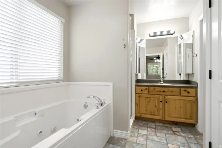Soaking tub with chrome fixtures under a window with blinds