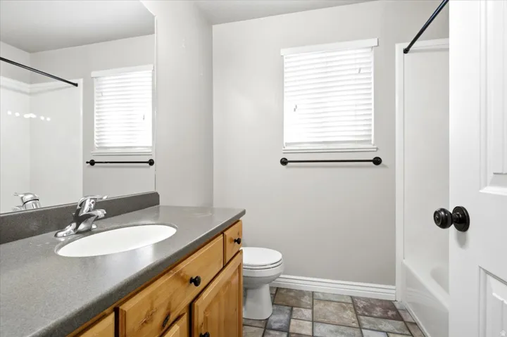 Bathroom featuring a wood vanity with a single basin sink, a gray countertop, and a large mirror