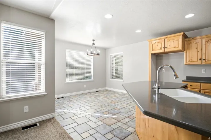 Kitchen island featuring a single-basin sink with a gooseneck faucet, dark countertop, and wood-finish cabinetry