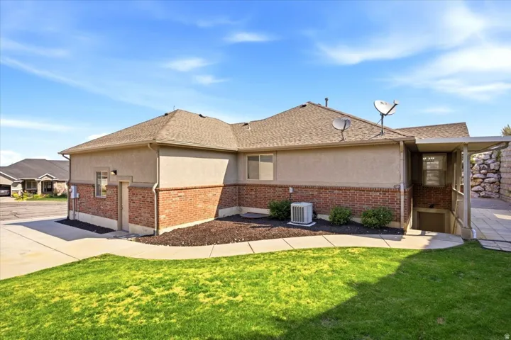 Exterior featuring a stucco and brick facade, a covered patio, and a sloped lawn