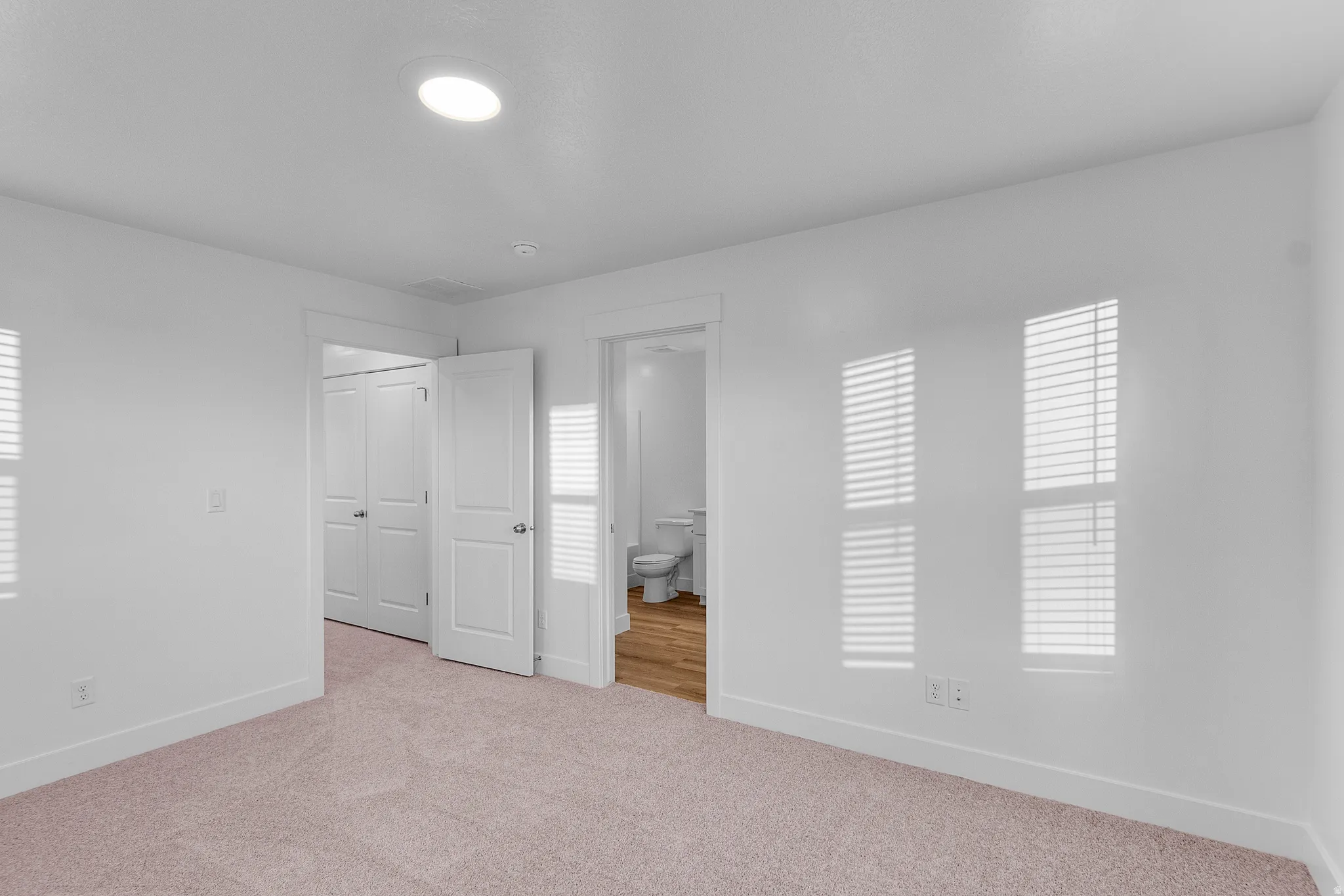 Carpeted room featuring white walls and baseboards