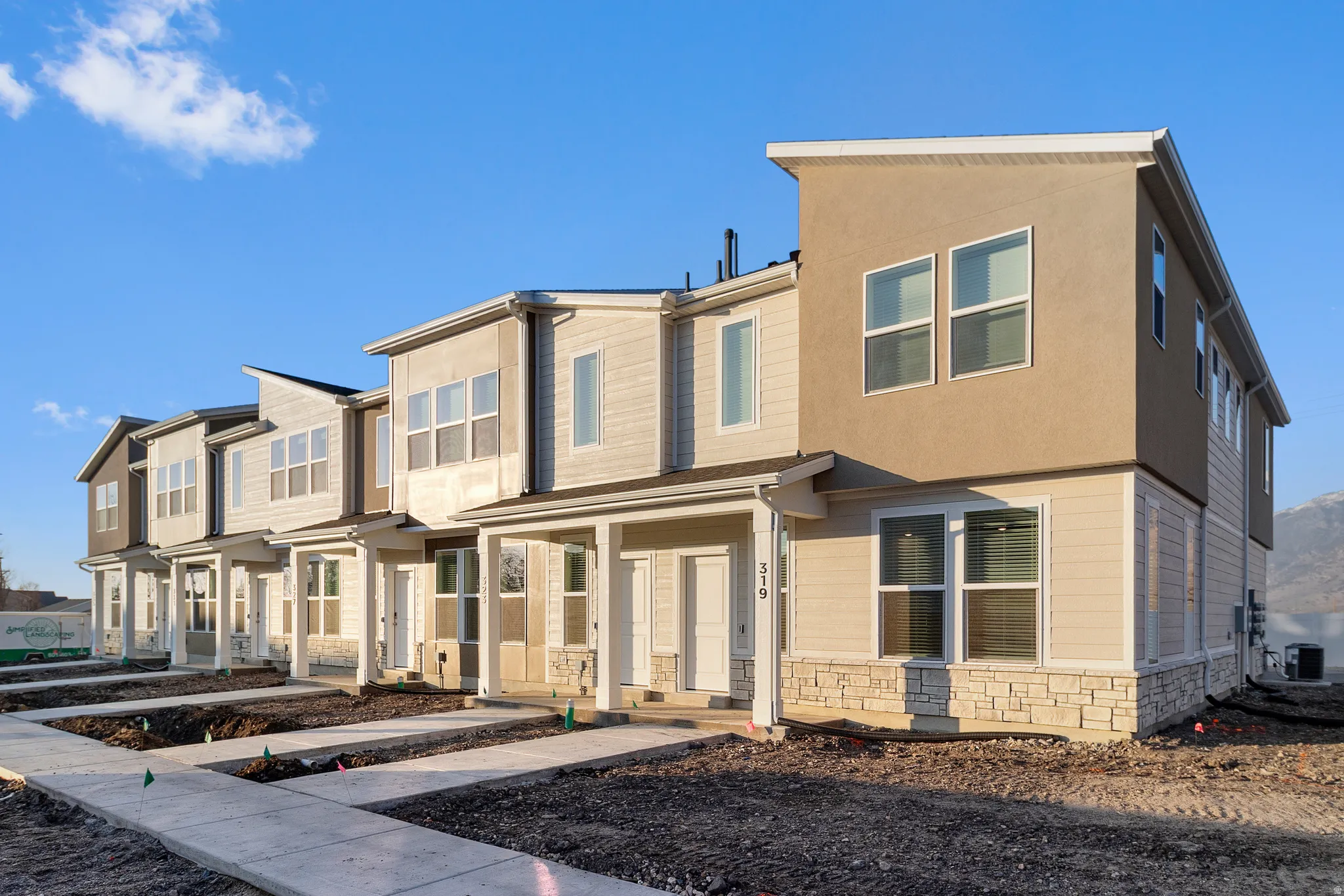 Contemporary townhome row featuring multi-textured facades, individual covered entryways, and prominent window configurations