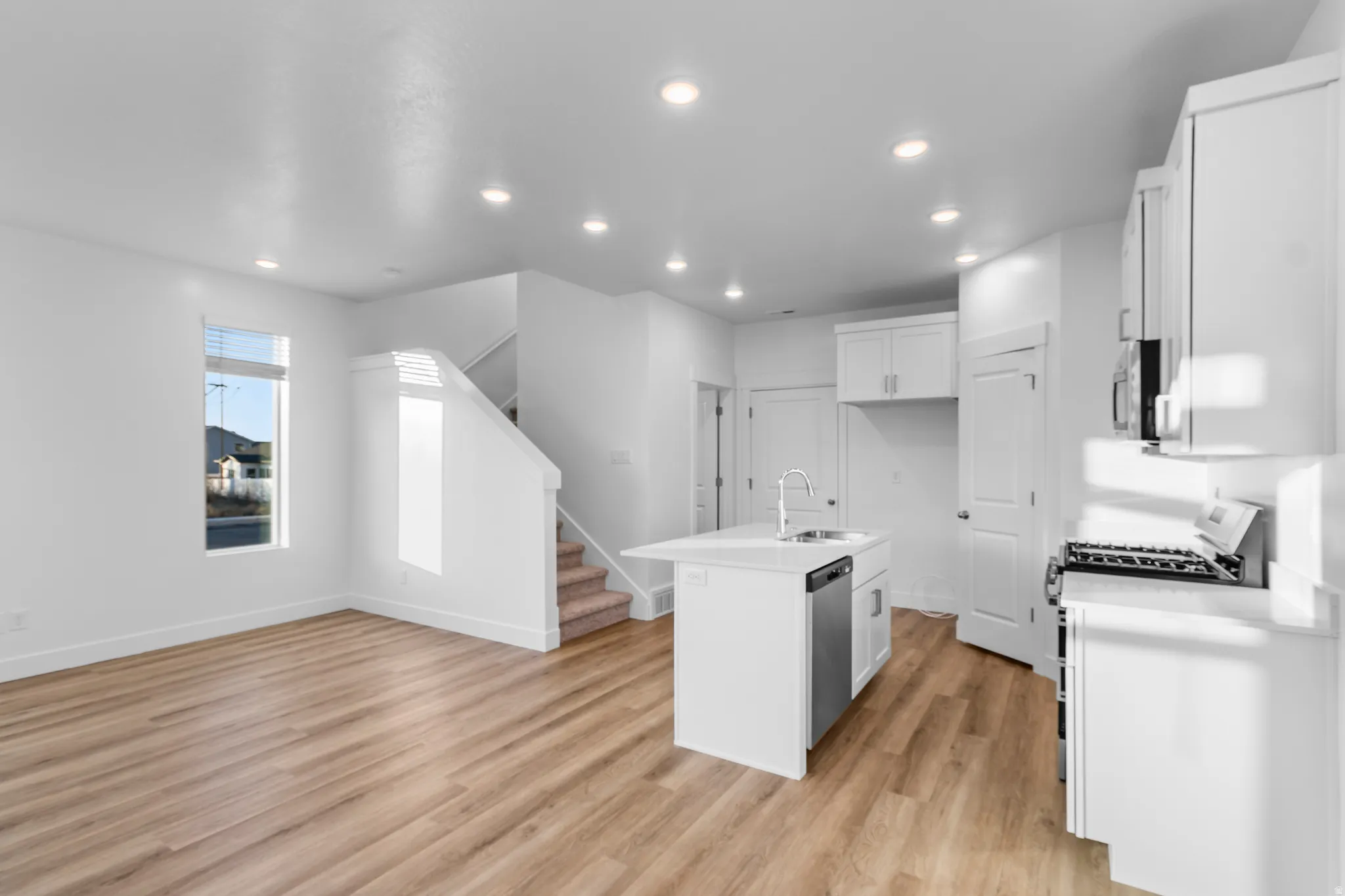 Open-concept living area featuring wood-finish flooring, recessed lighting, and a modern kitchen