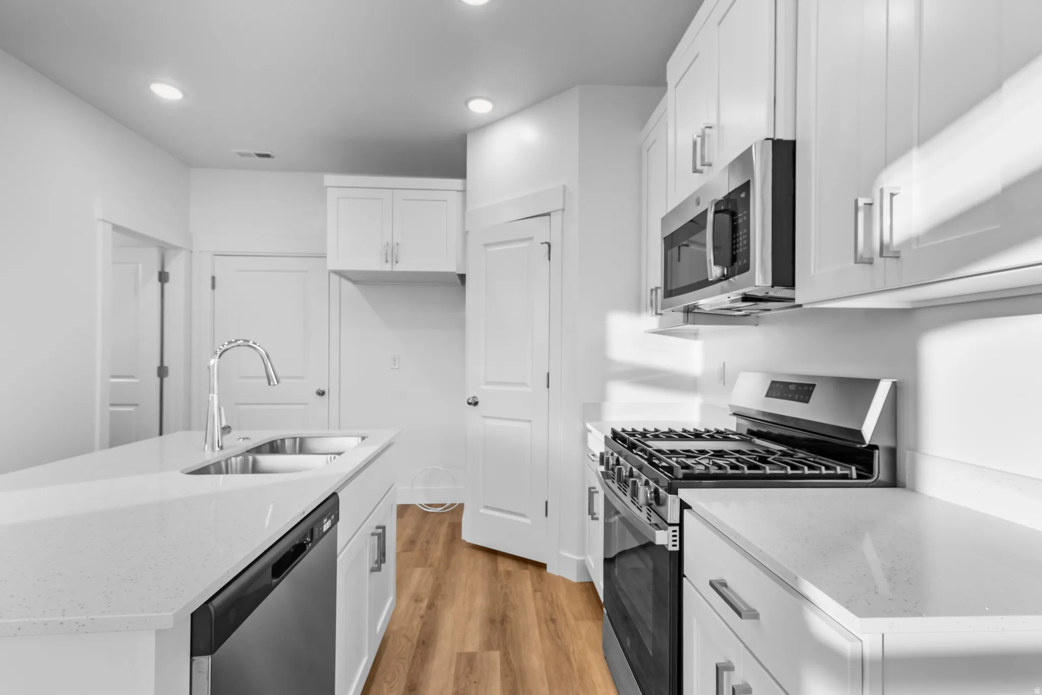 Modern kitchen featuring white shaker cabinetry and light-toned countertops