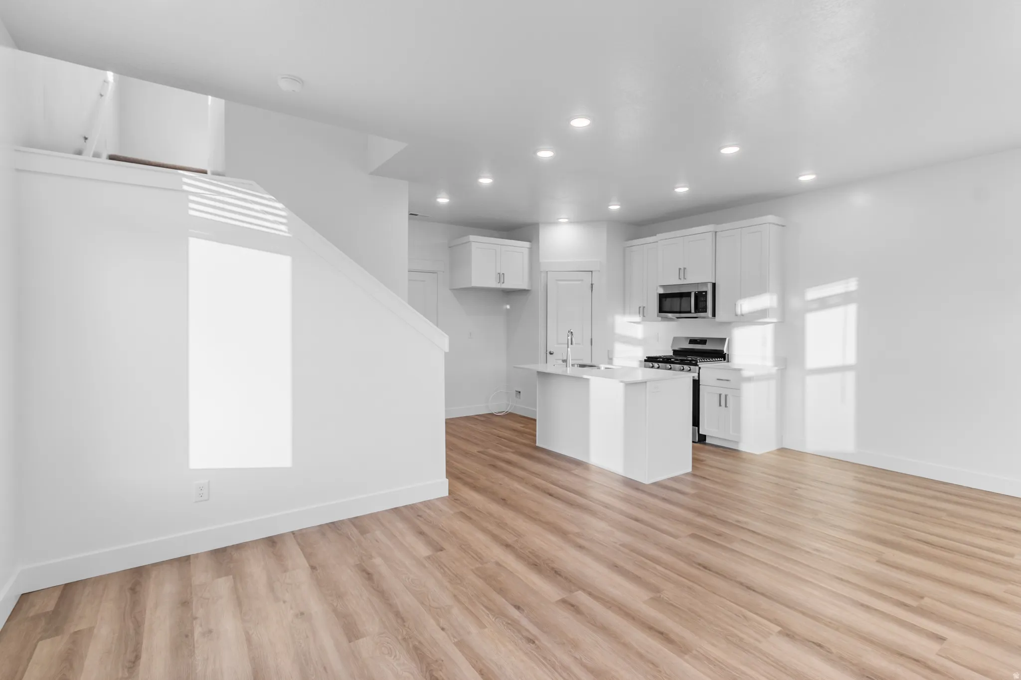 Open-concept living space featuring wood-finish flooring, recessed lighting, and a contemporary kitchen