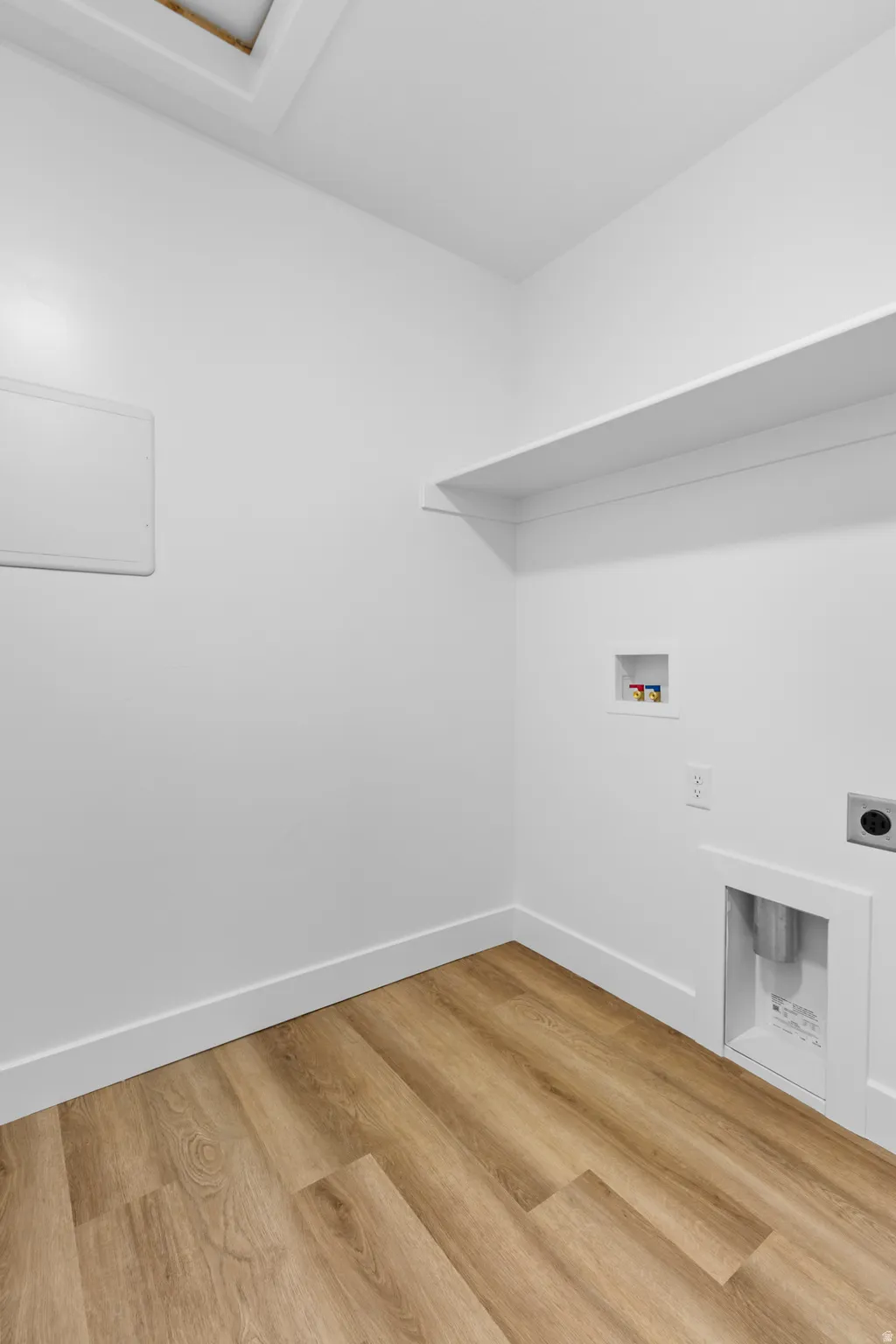 Utility space featuring wood-finish flooring, white baseboards, and a skylight