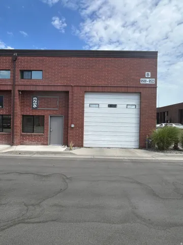 Red brick facade featuring a white overhead door and multiple windows