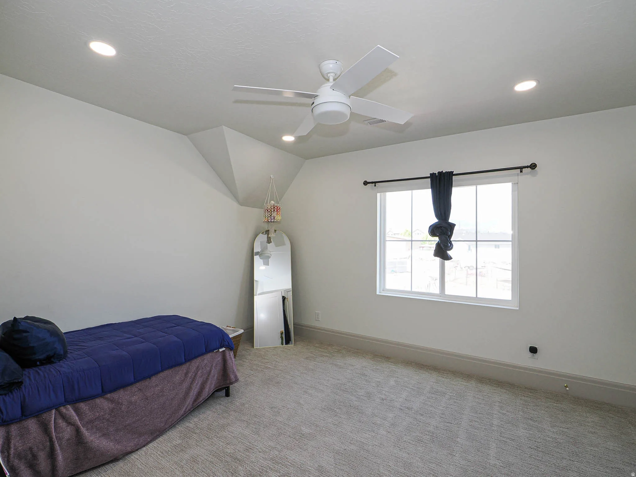 Carpeted room featuring a white ceiling fan, recessed lighting, a window with grid patterns, and substantial baseboards