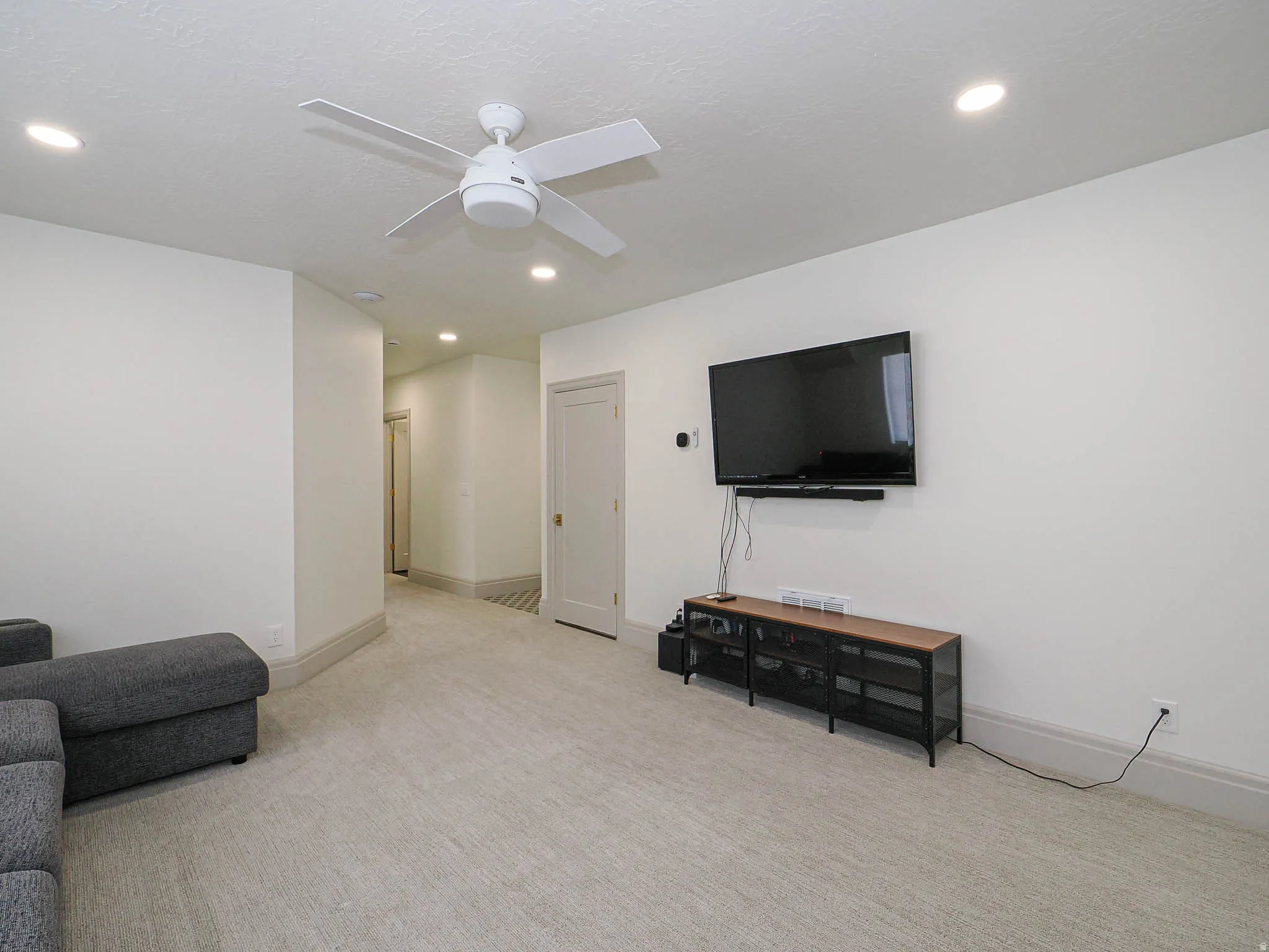 Carpeted room featuring a ceiling fan, recessed lighting, and light-toned walls with matching baseboards