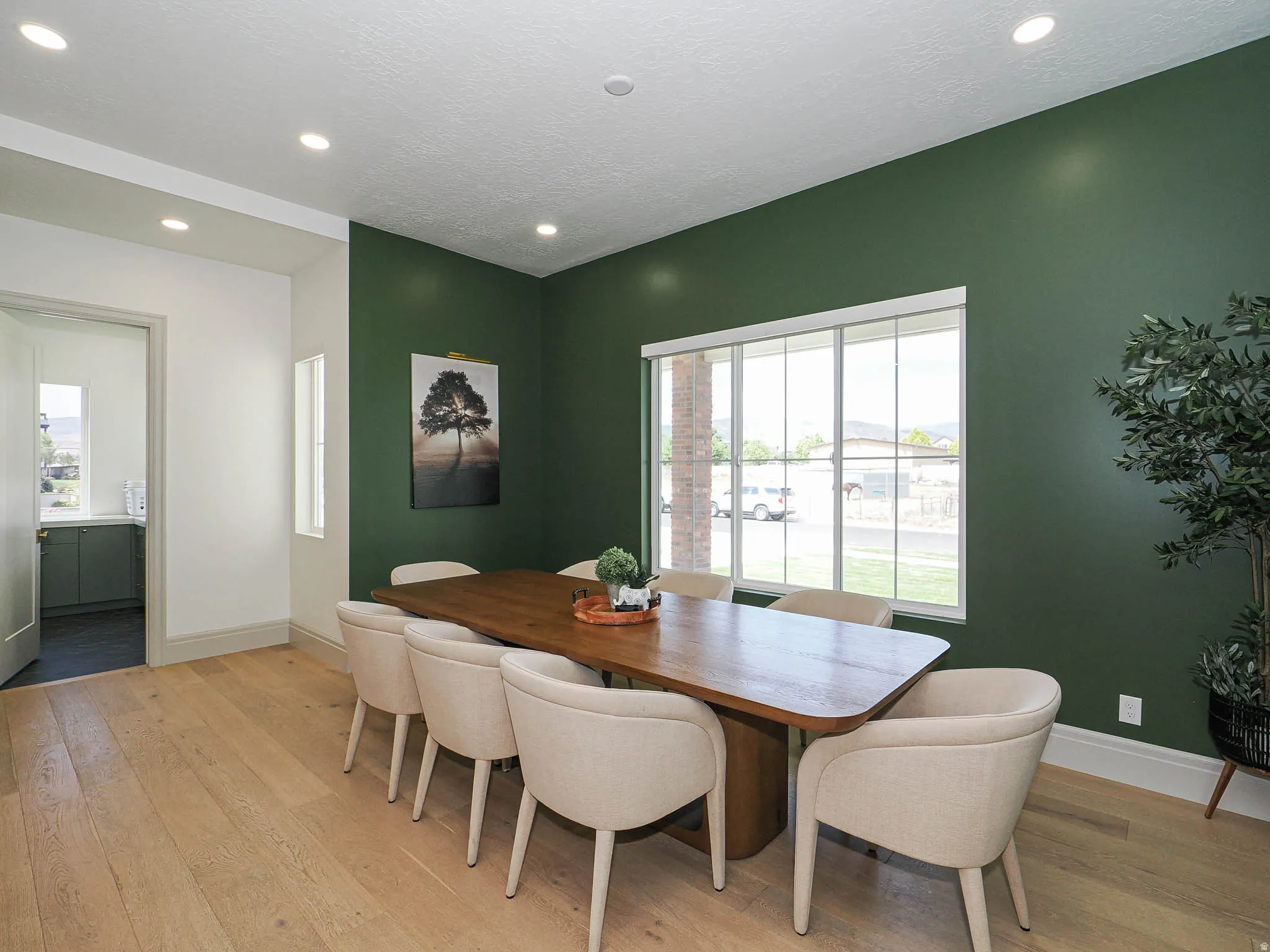 Hardwood-style flooring throughout, featuring recessed ceiling lighting, a large picture window, and a dedicated room entry