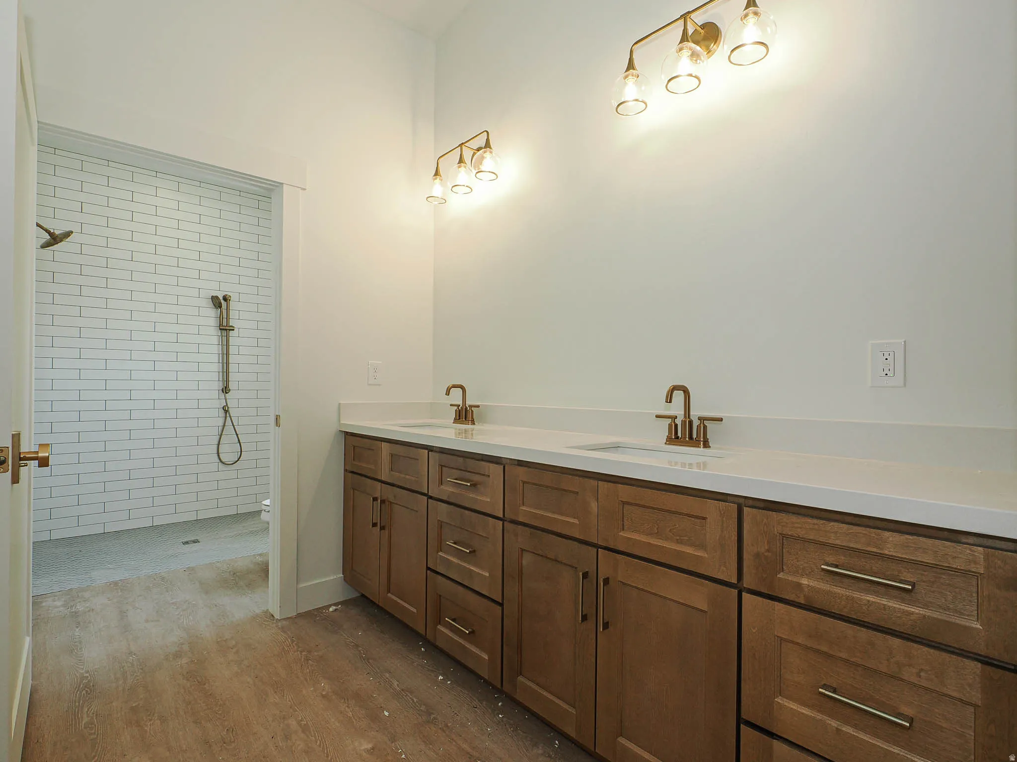 Double vanity with integrated sinks, light-toned countertops, and brass-finish fixtures