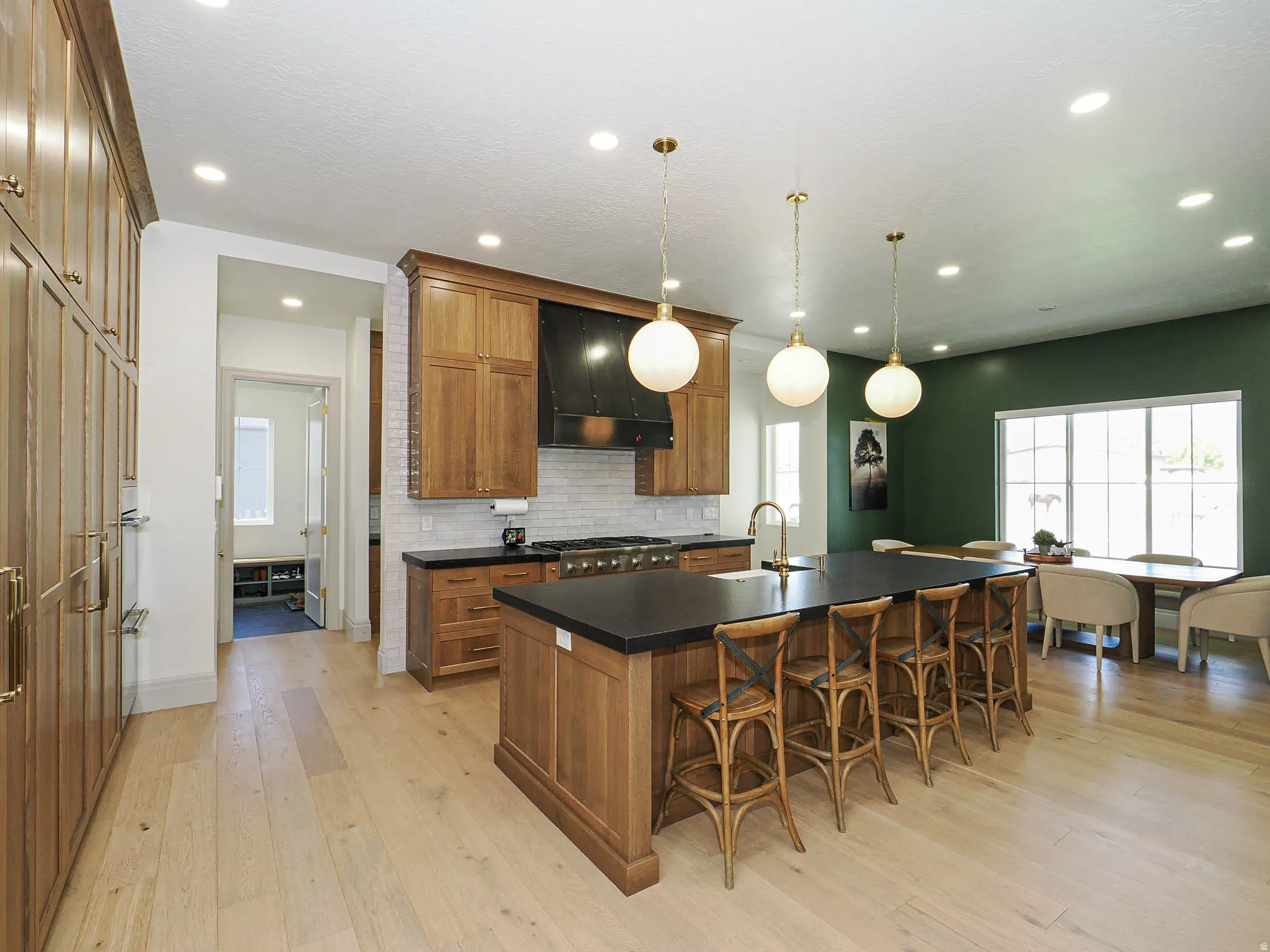 Gourmet kitchen featuring a large central island with seating, stainless steel appliances, wood-finish cabinetry, and light wood-finish flooring