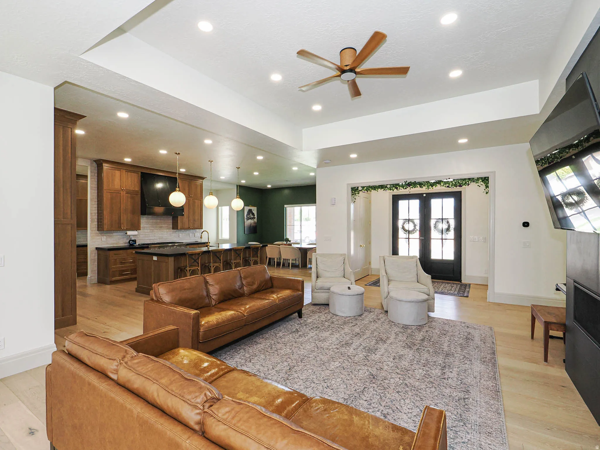 Expansive living area with wood-finish flooring, recessed lighting, and a tray ceiling