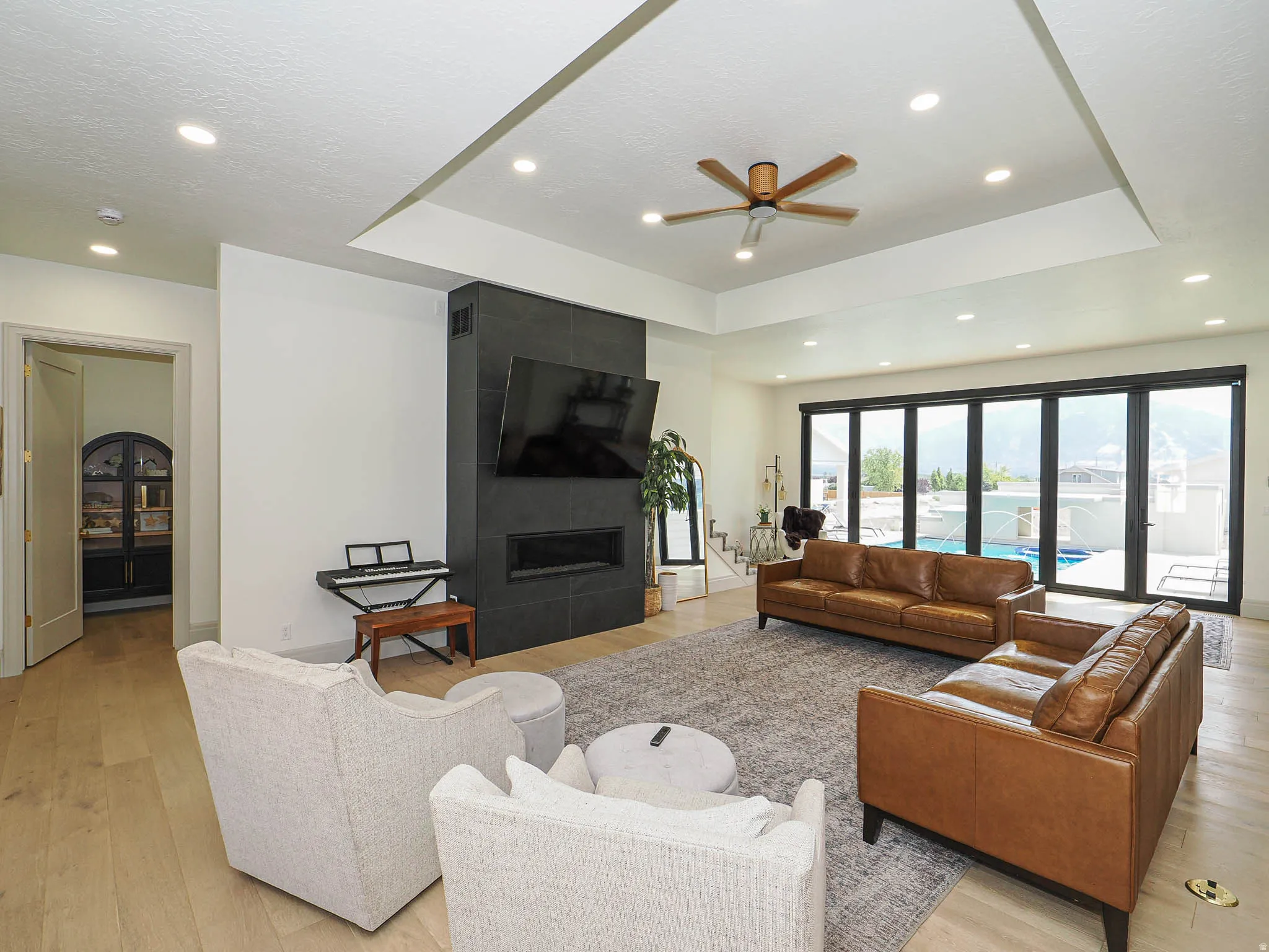 Spacious living area featuring wood-finish flooring, a contemporary fireplace with a dark stone surround, and abundant recessed lighting