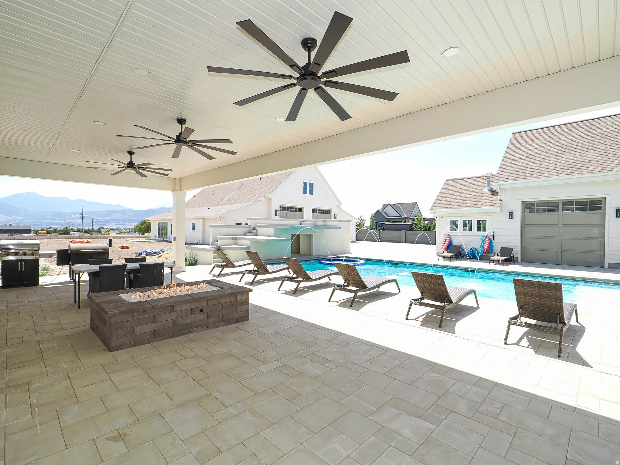 Expansive covered patio featuring a paver surface and three ceiling fans