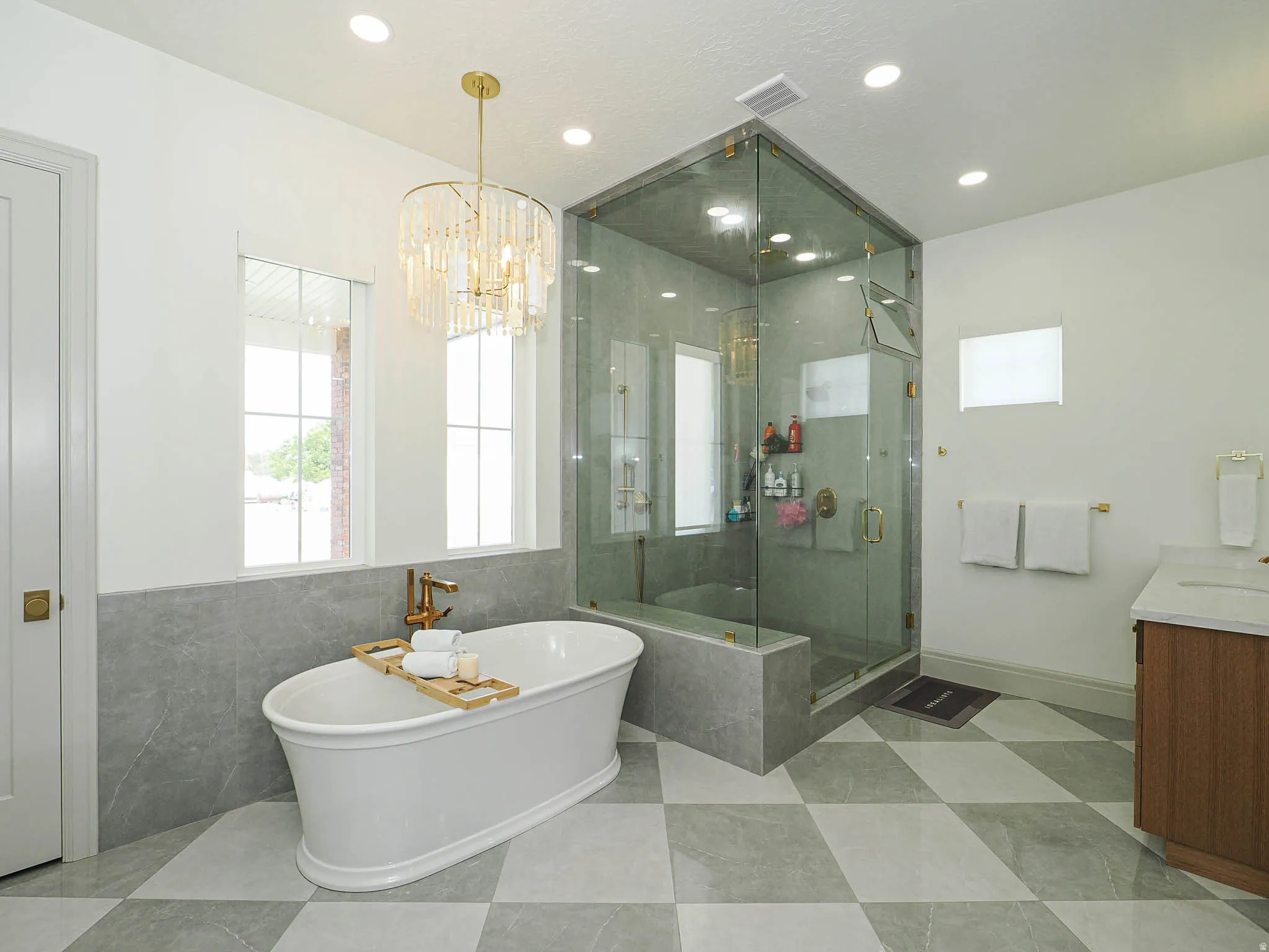 Freestanding soaking tub with gold-tone fixtures, complemented by a spacious glass-enclosed shower