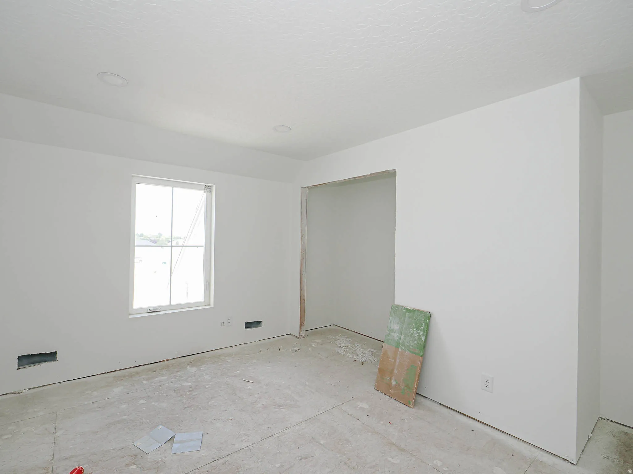 Room under construction featuring a window, recessed ceiling lighting, and a doorway opening