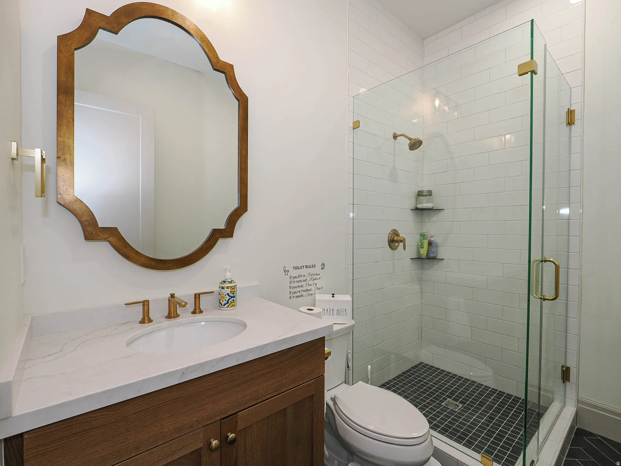 Bathroom featuring a glass-enclosed shower with subway tile surround and dark hex tile flooring