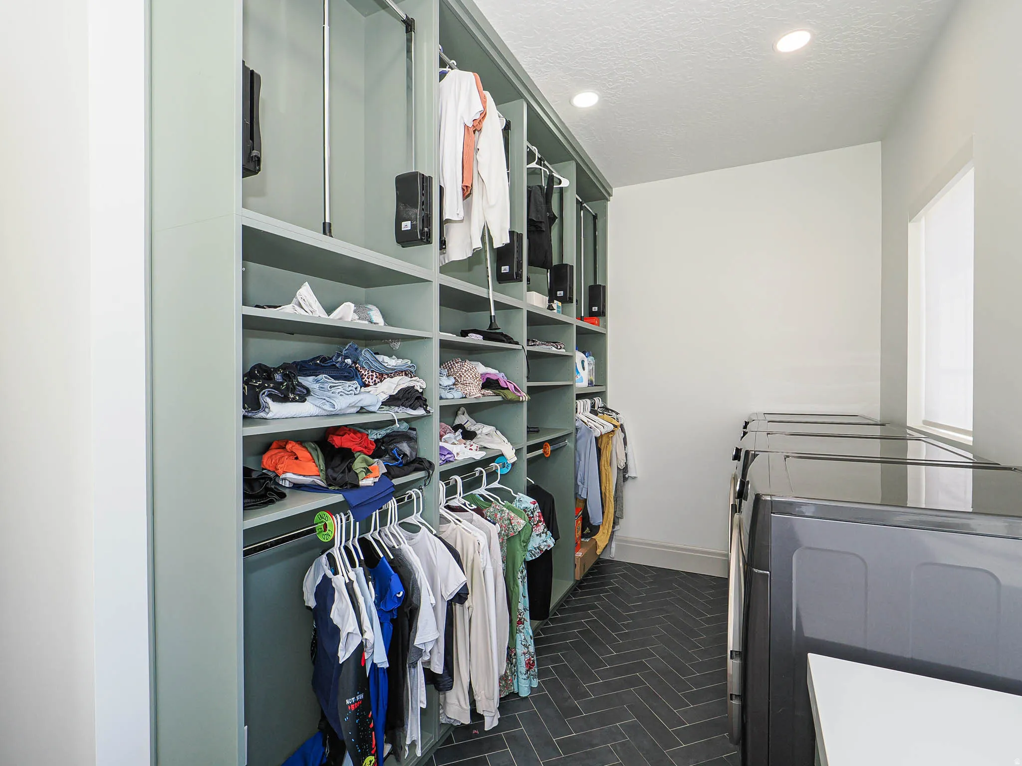 Laundry room featuring a herringbone tile floor, recessed lighting, and a window with blinds