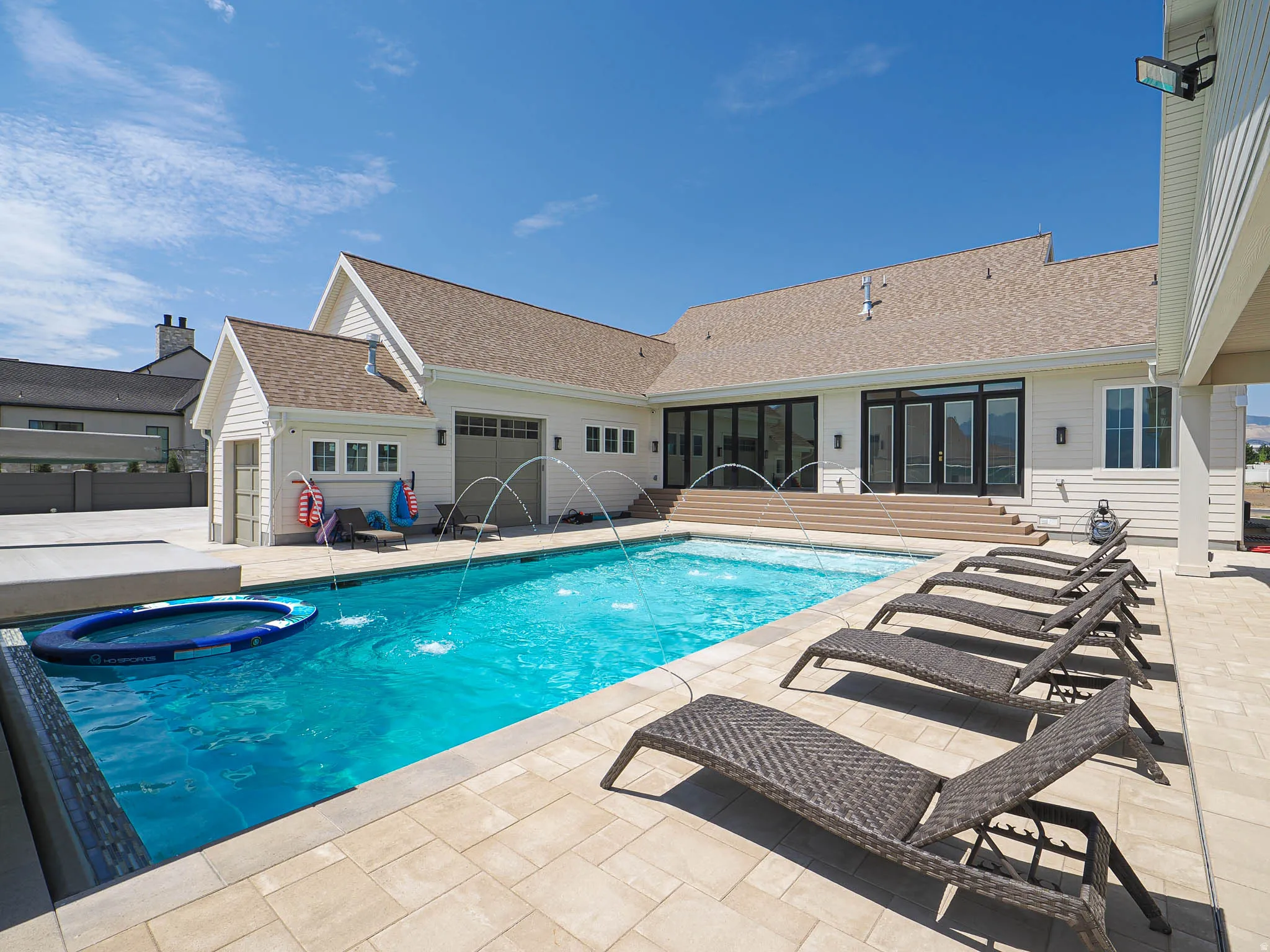 Outdoor swimming pool featuring water jets and a perimeter of light-toned paver stones
