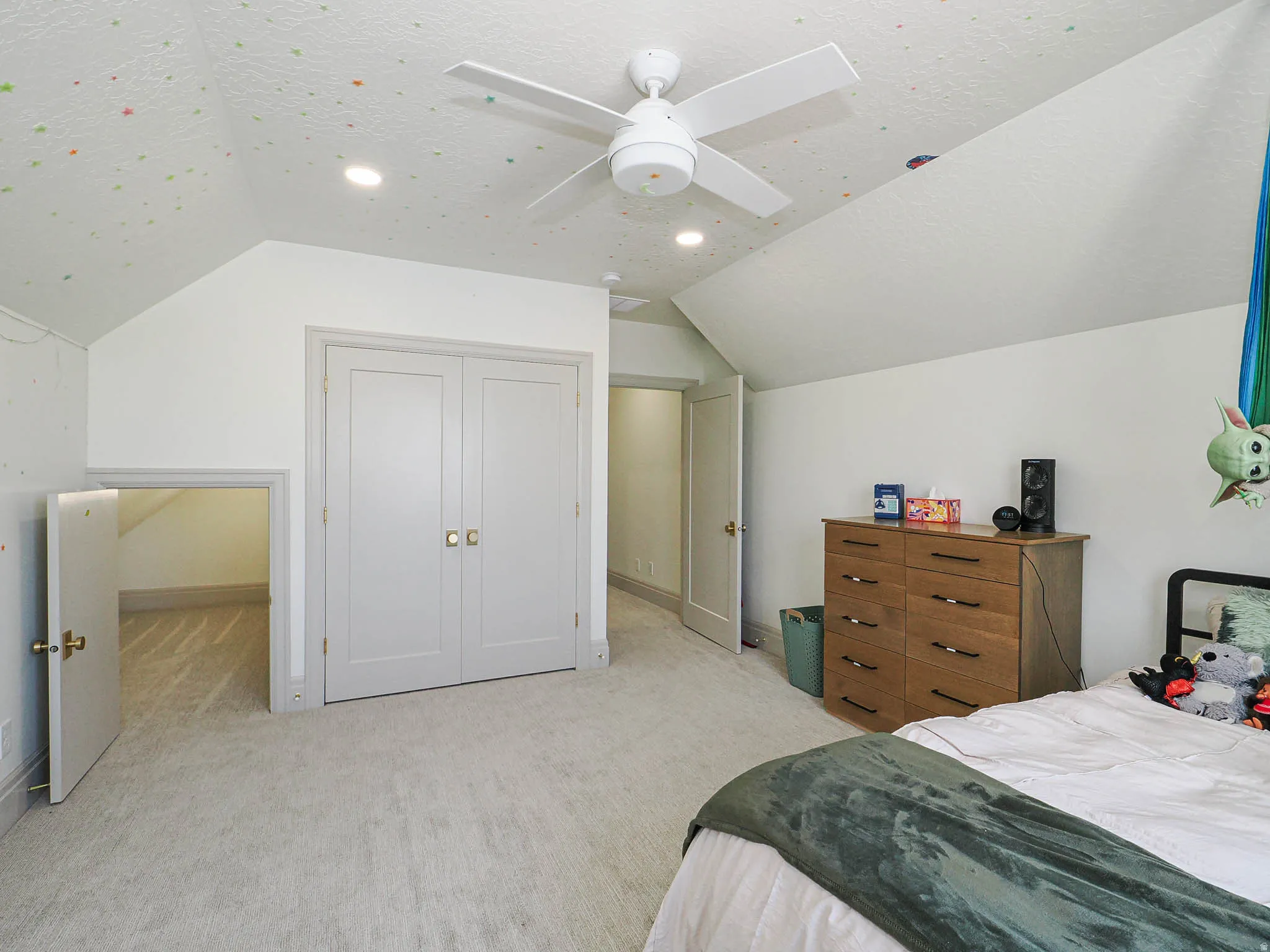 Carpeted room featuring a ceiling fan with integrated lighting, recessed ceiling lights, and angled ceilings