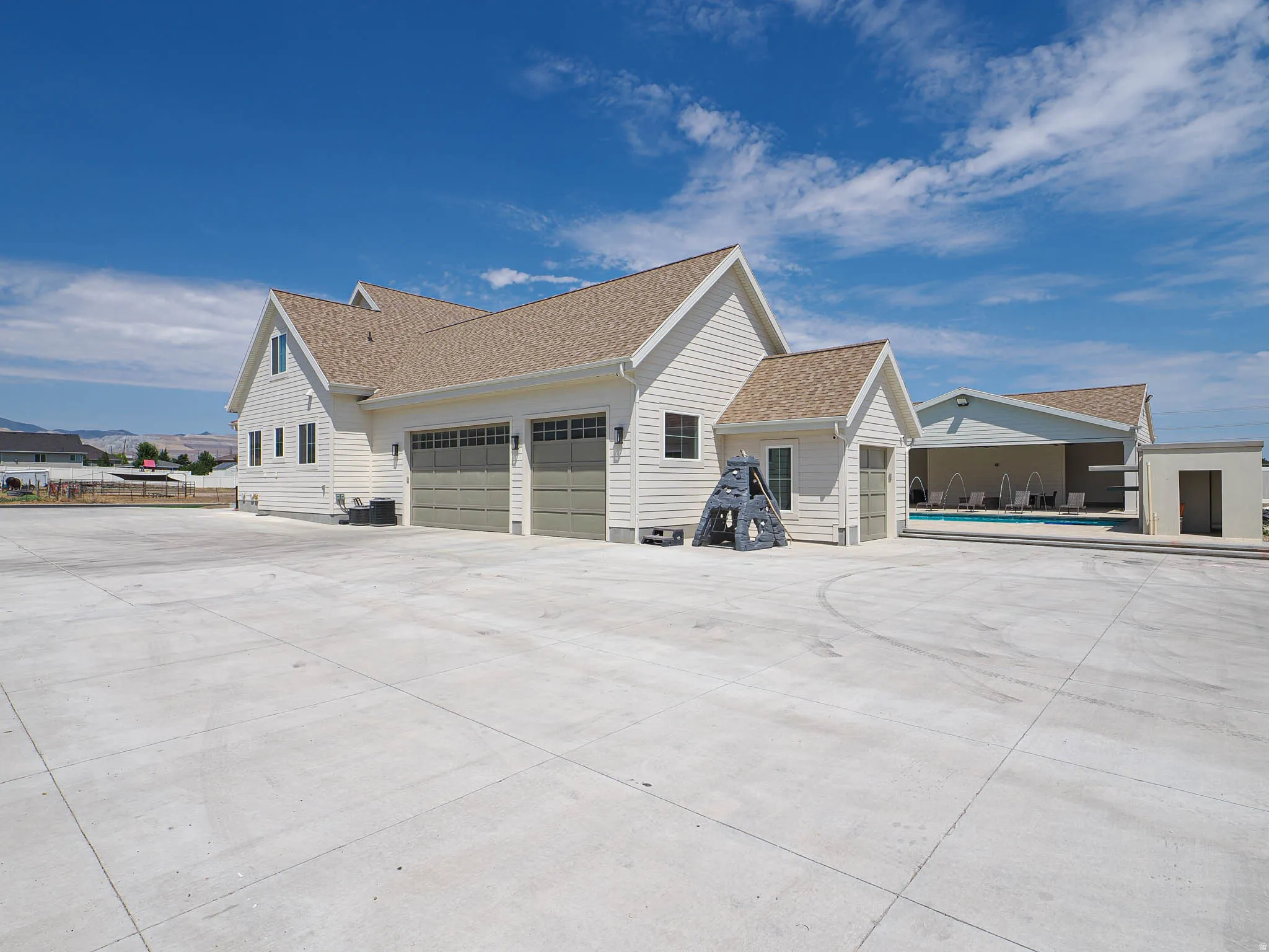 Expansive concrete surfacing with a three-car garage featuring segmented light-colored doors