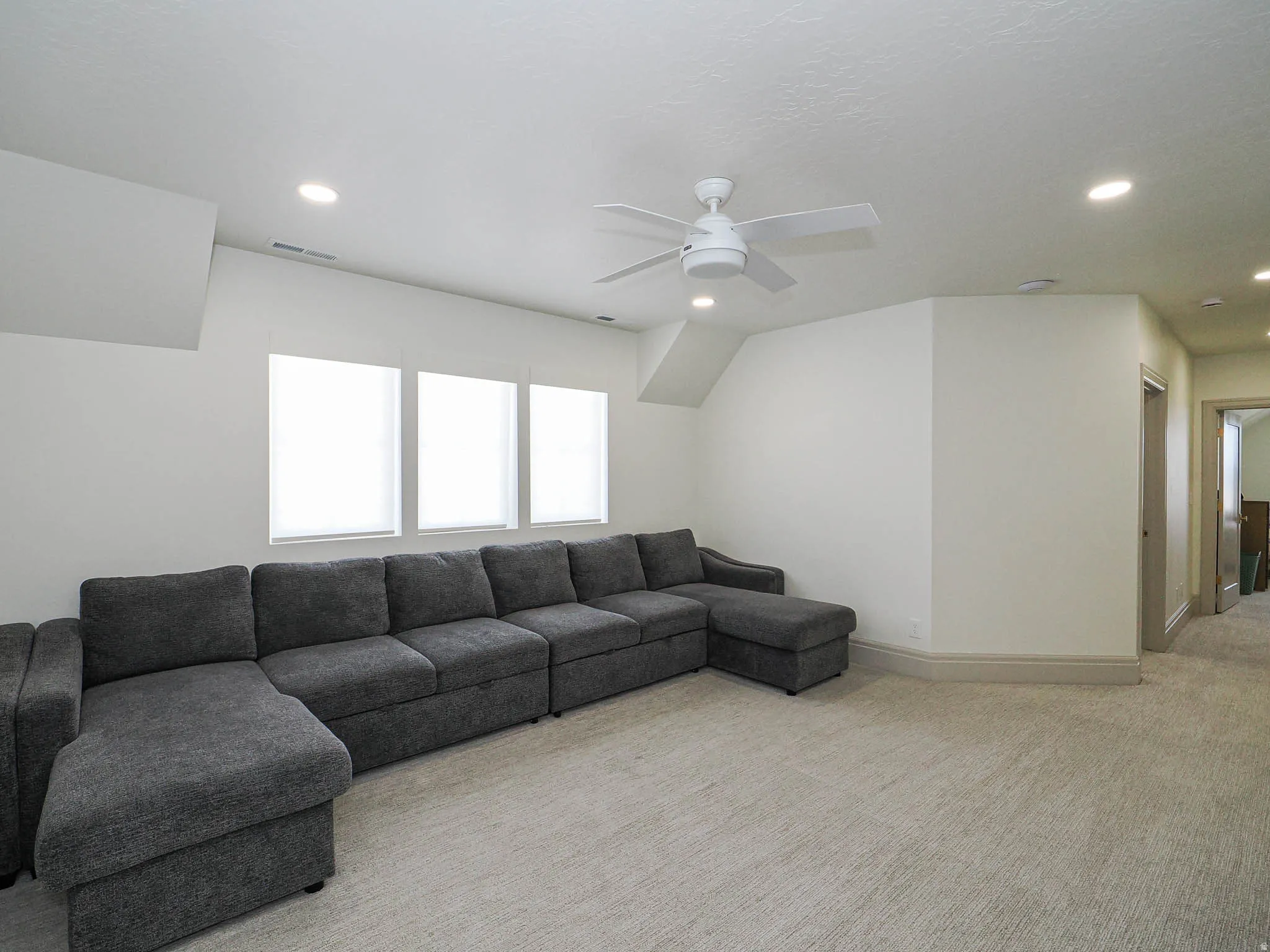 Spacious bonus room featuring three windows with blinds, recessed lighting, and a ceiling fan