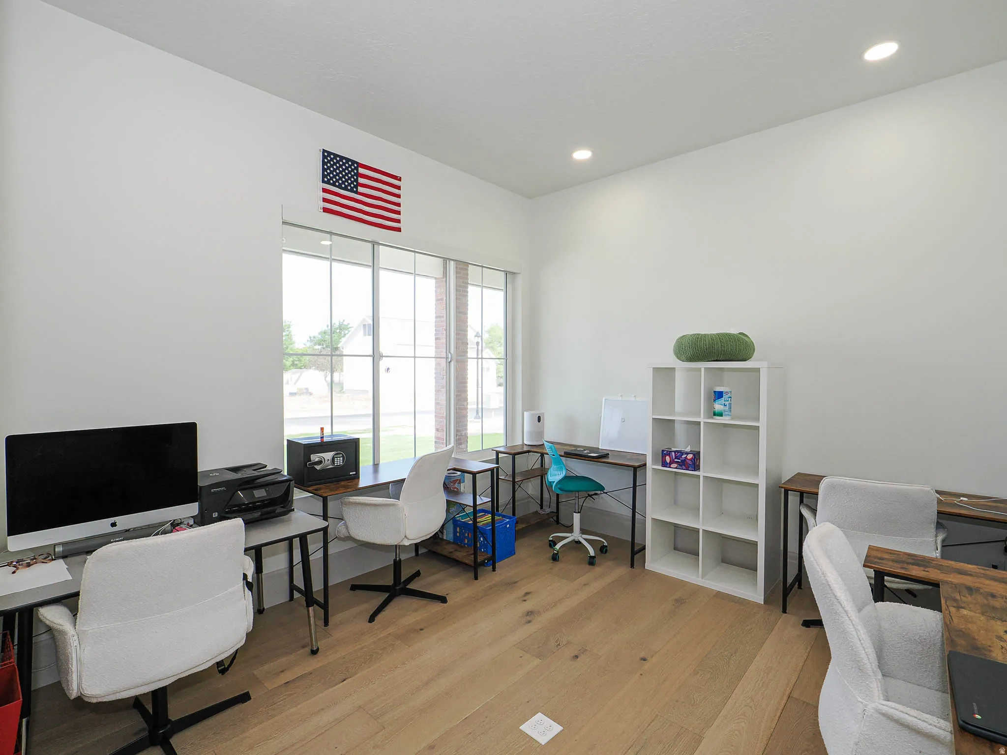 Spacious room featuring light wood-finish flooring, recessed lighting, and large windows with multi-pane detailing
