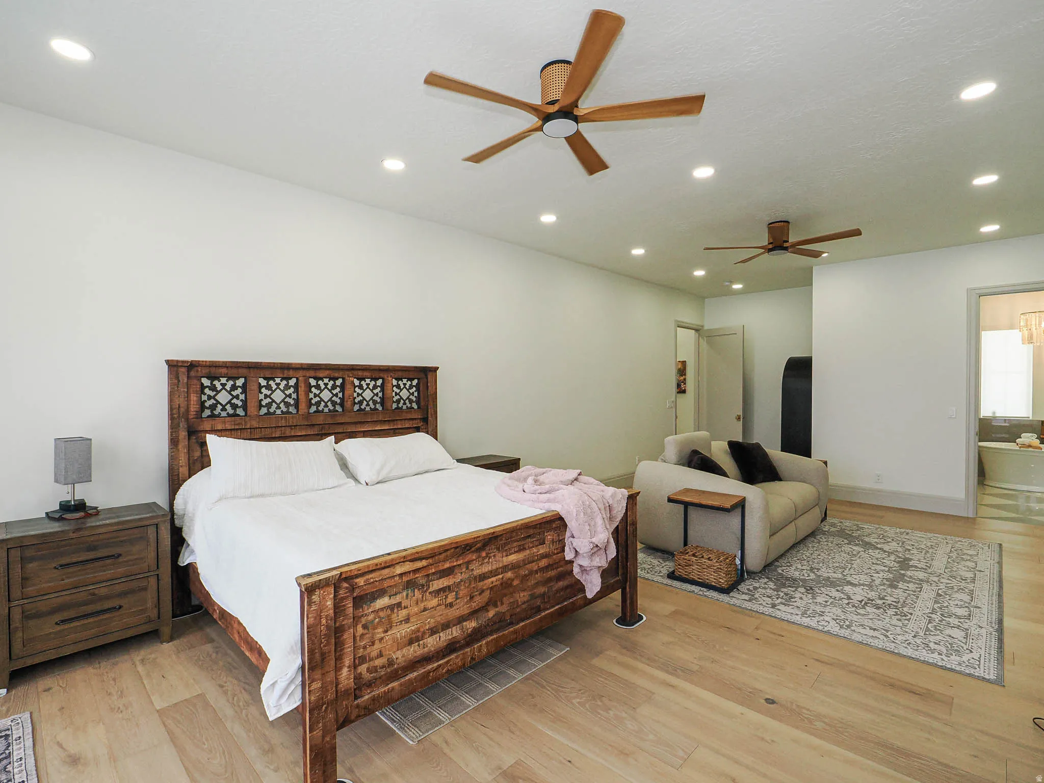 Spacious room featuring light wood-finish flooring, recessed lighting, and dual ceiling fans