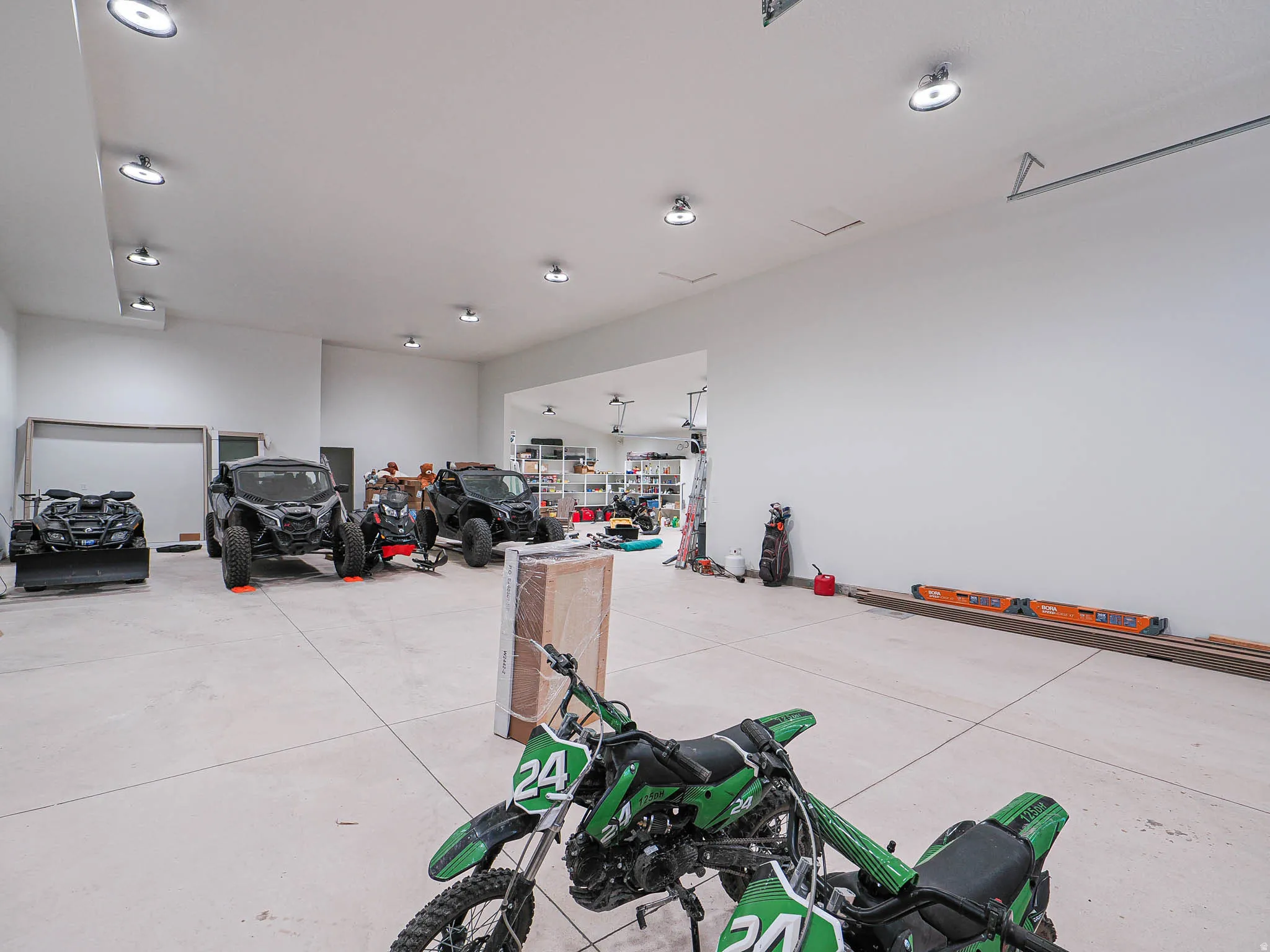 Spacious garage featuring a concrete floor, multiple ceiling-mounted light fixtures, and white painted walls