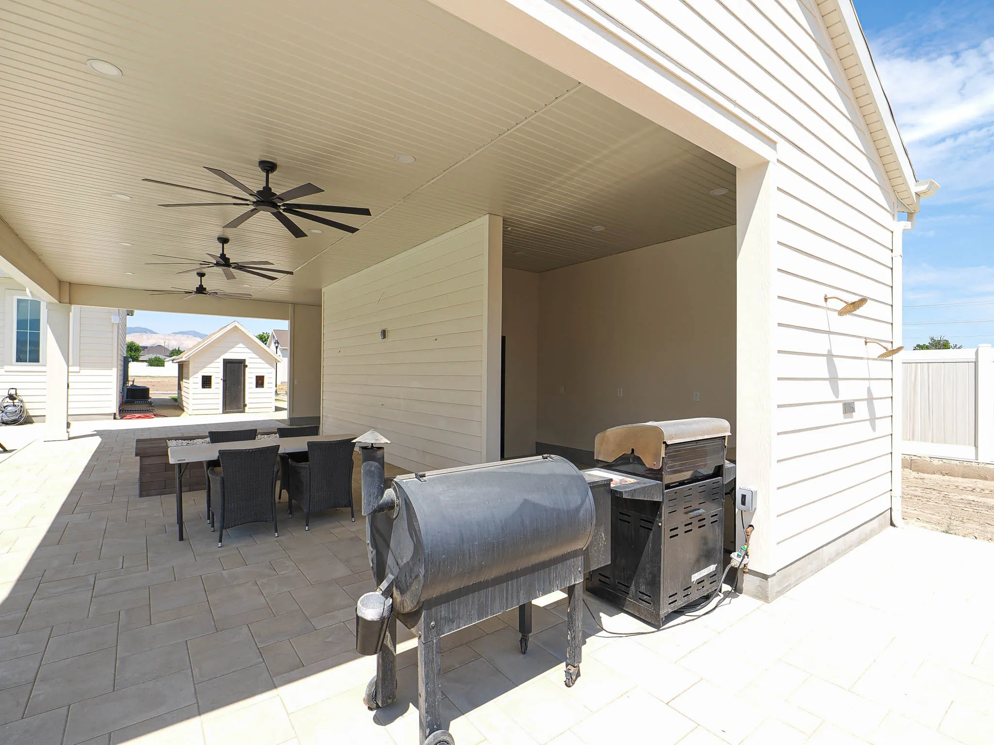 Expansive covered patio featuring multiple ceiling fans, recessed lighting, and a paved surface