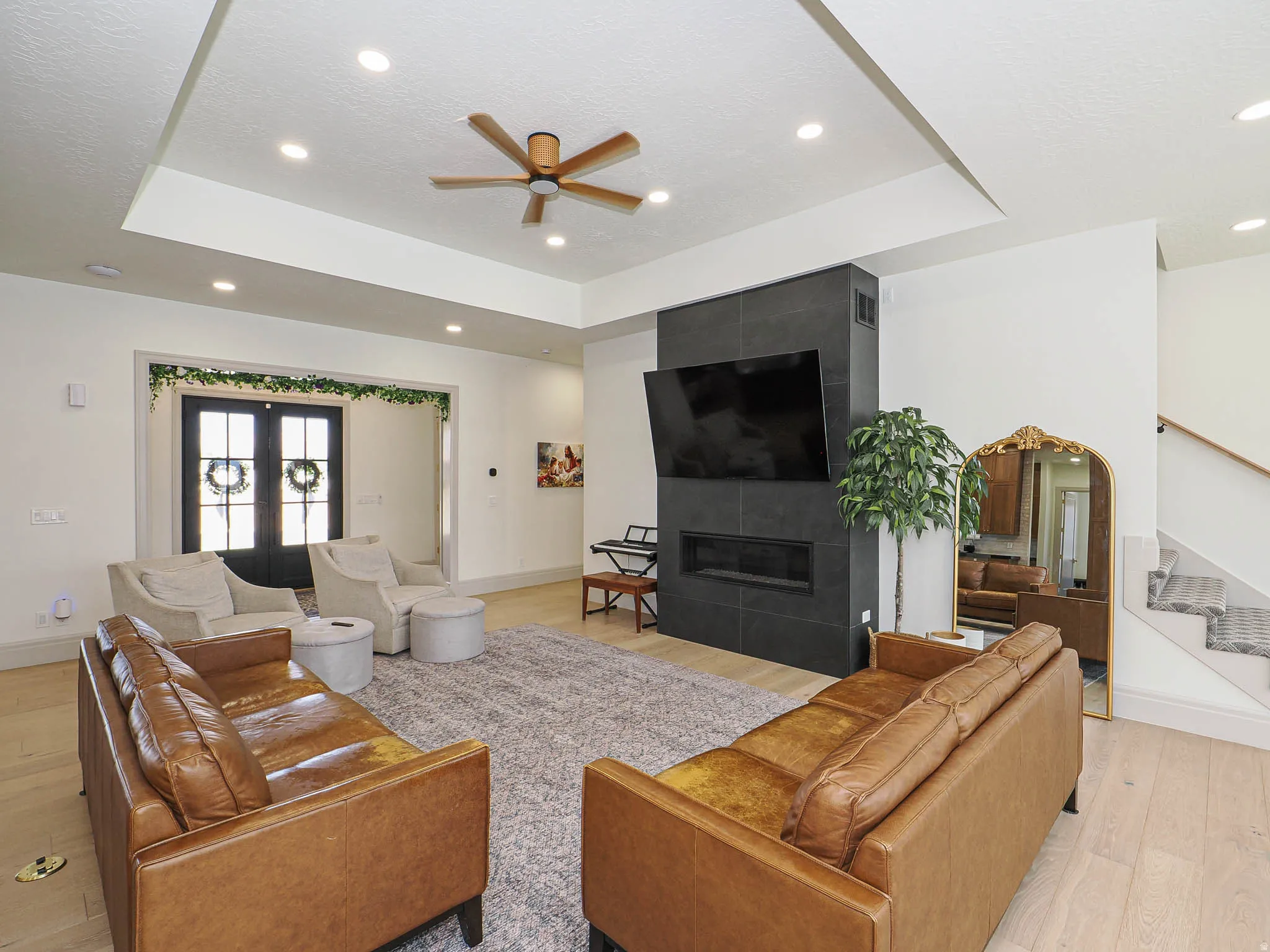 Living room featuring a dark tile fireplace with an integrated linear firebox, a tray ceiling, recessed lighting, and wood-finish flooring