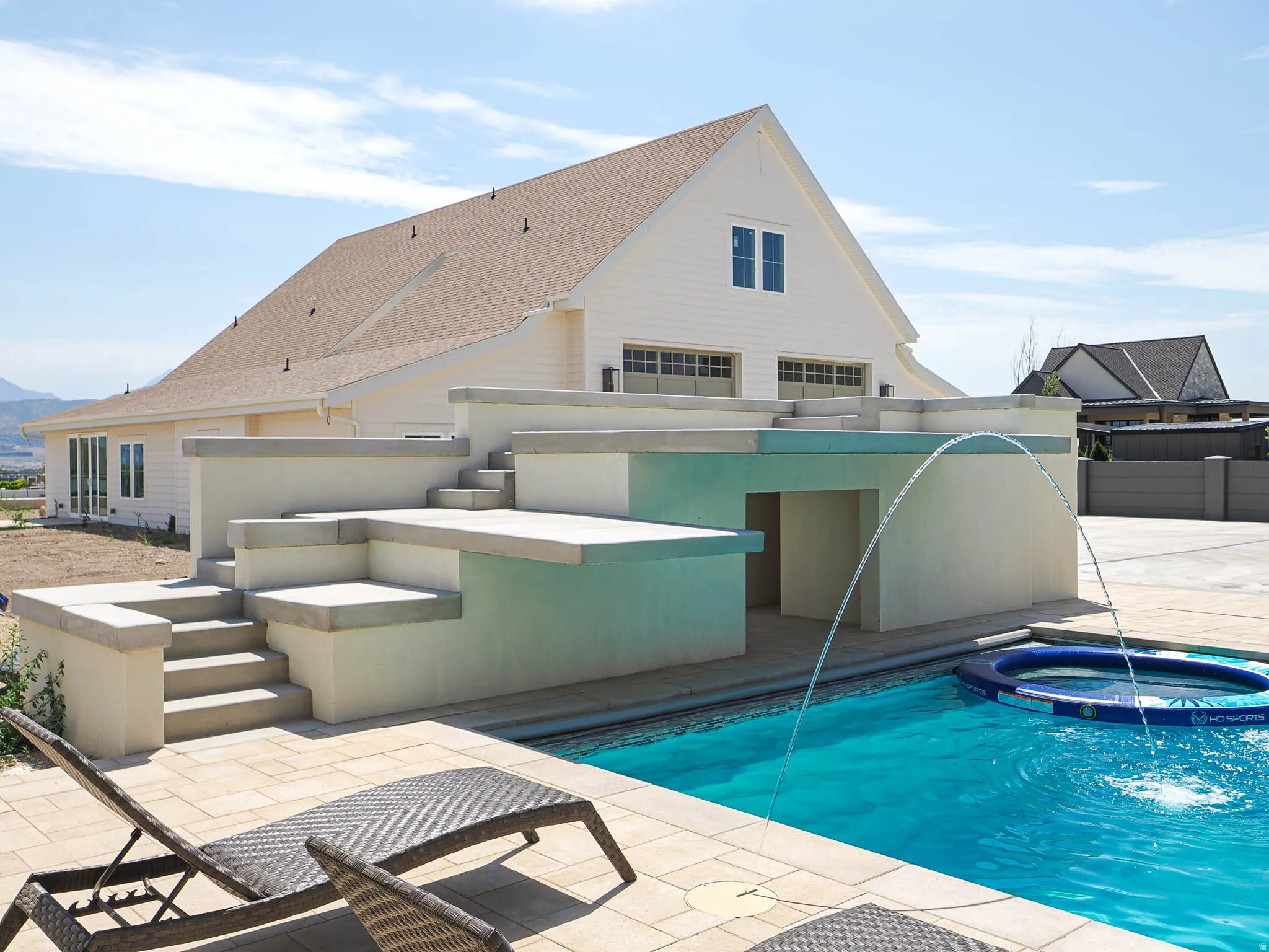 Outdoor swimming pool featuring a water fountain, surrounding patio, and tiered concrete steps