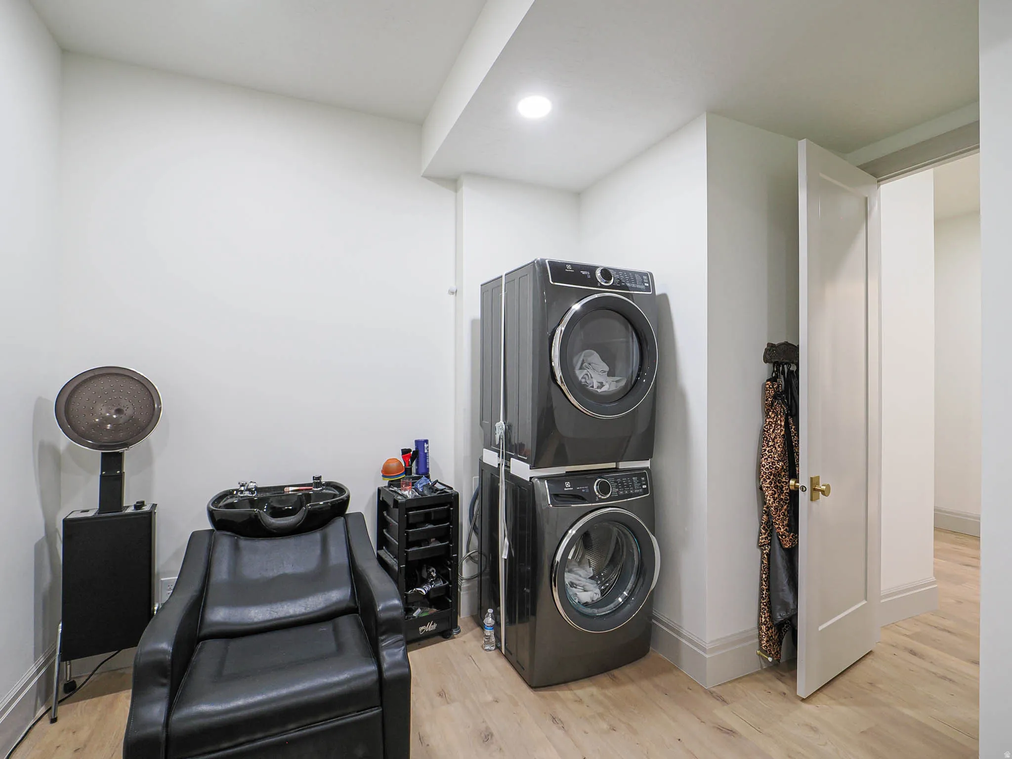 Laundry area featuring stacked washer and dryer units, recessed lighting, and wood-finish flooring