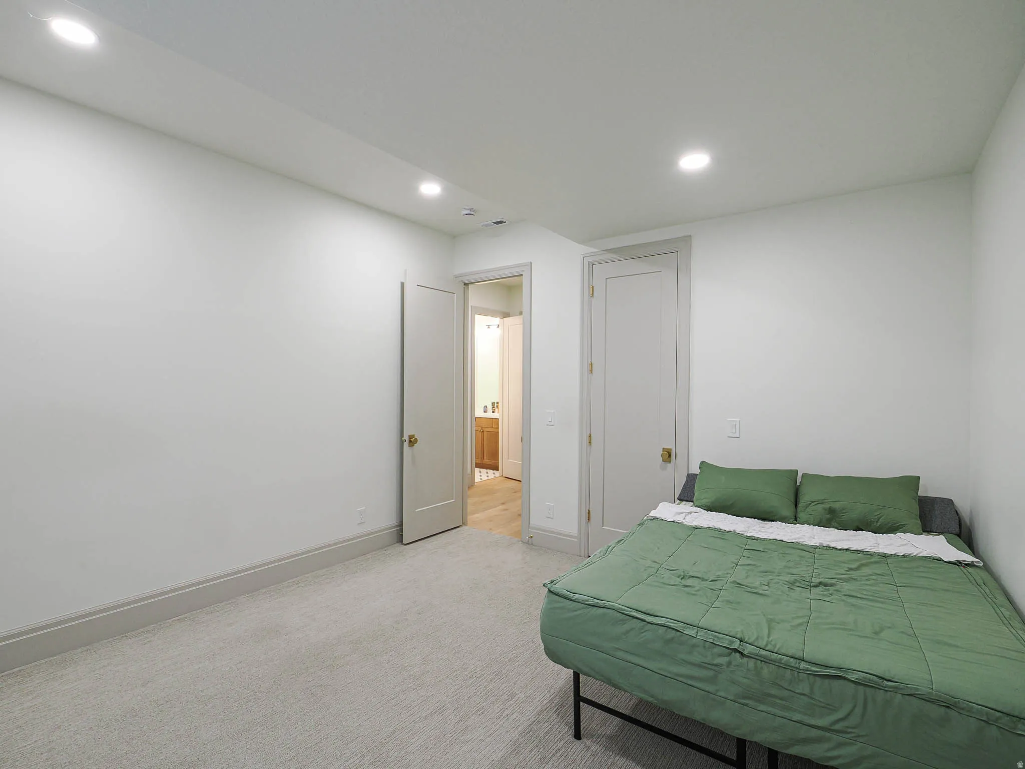 Neutral white walls with recessed lighting and light-colored carpeting