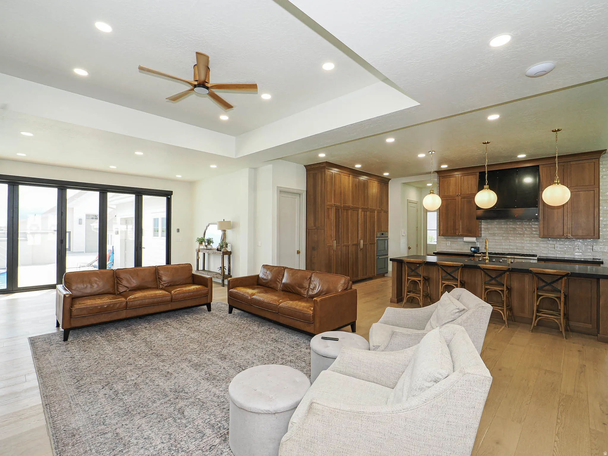 Expansive open-concept living area featuring light wood-finish flooring, recessed lighting, and a modern ceiling fan