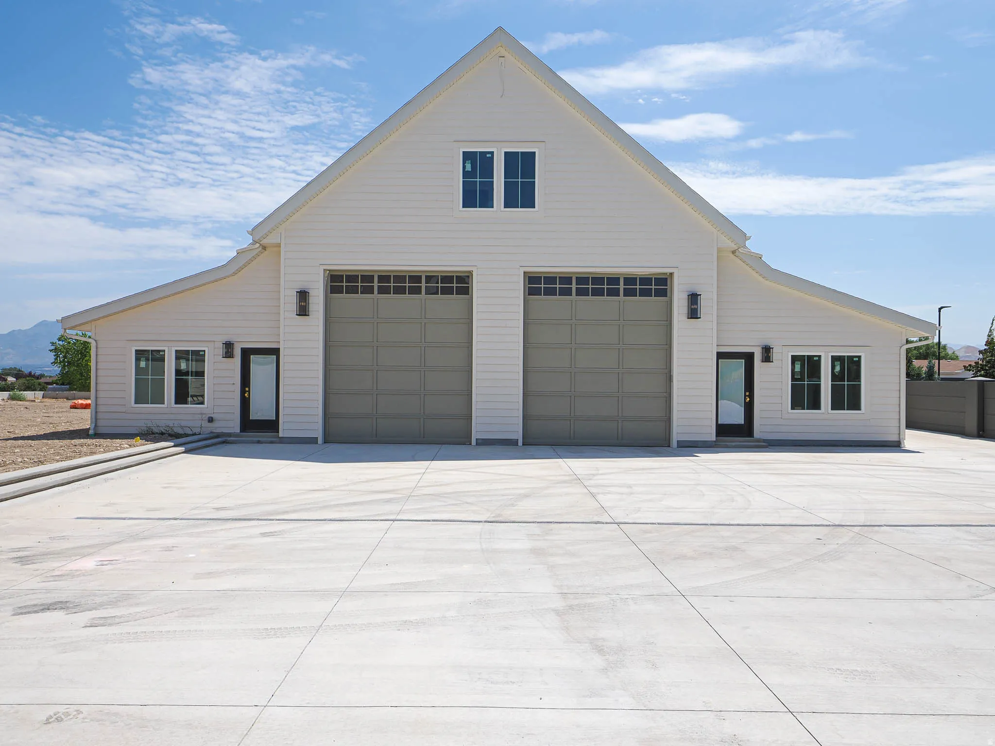 Two-story structure with white horizontal siding and a prominent gable roofline