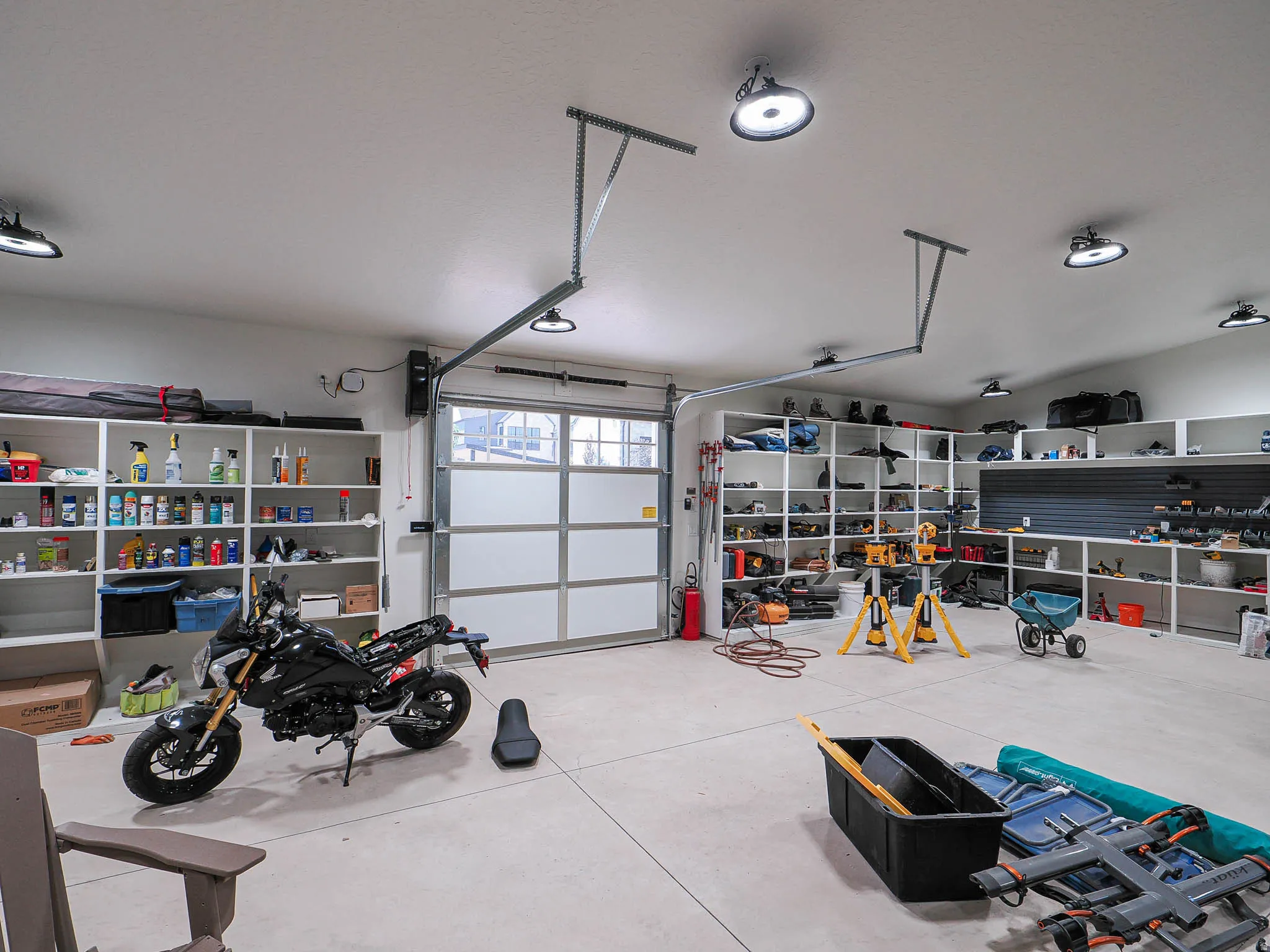 Spacious garage featuring a concrete floor, overhead lighting fixtures, a translucent panel garage door, and built-in shelving systems