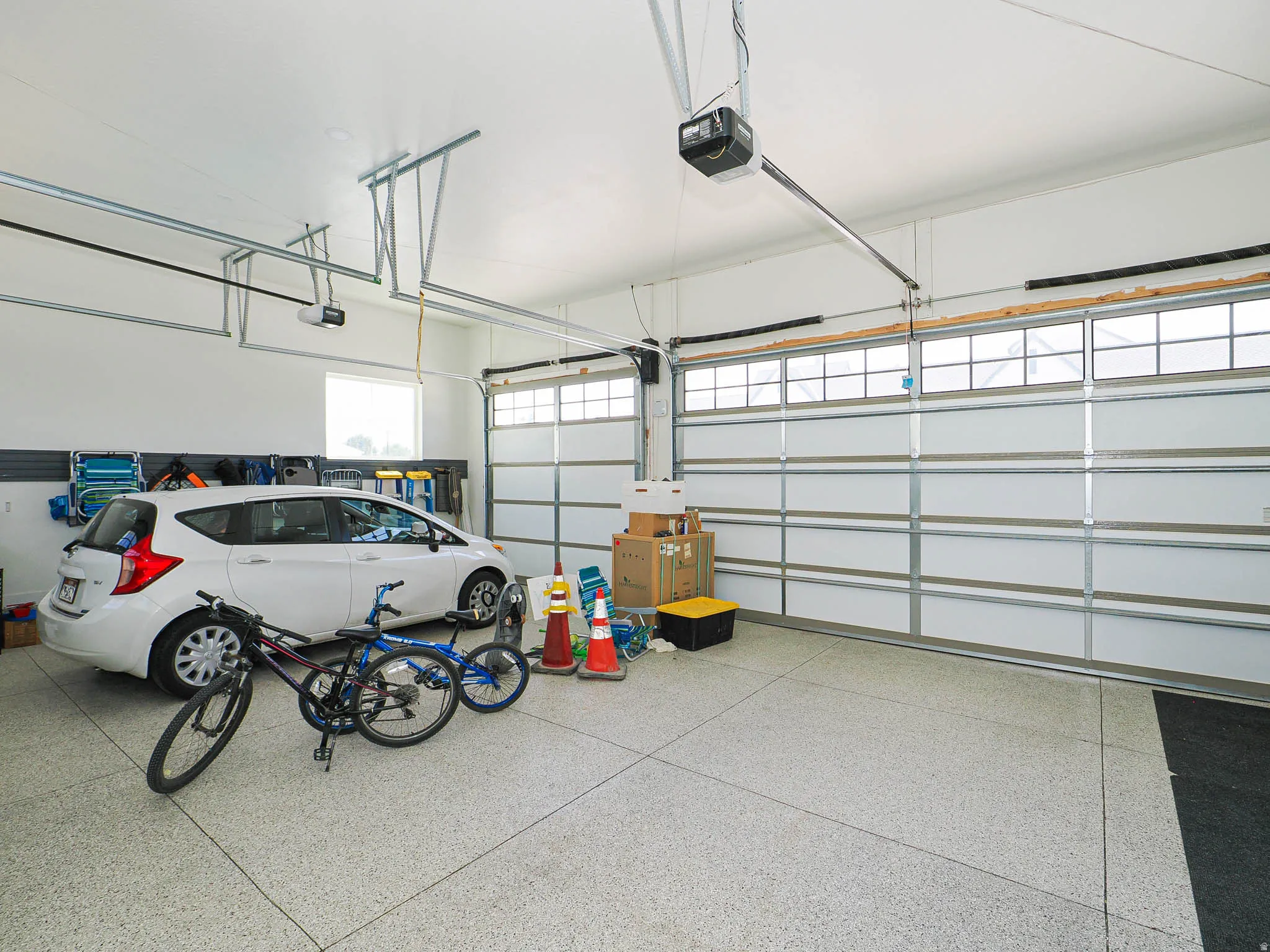 Two-car garage featuring an epoxy-coated concrete floor, two automatic garage door openers, and track-mounted wall storage