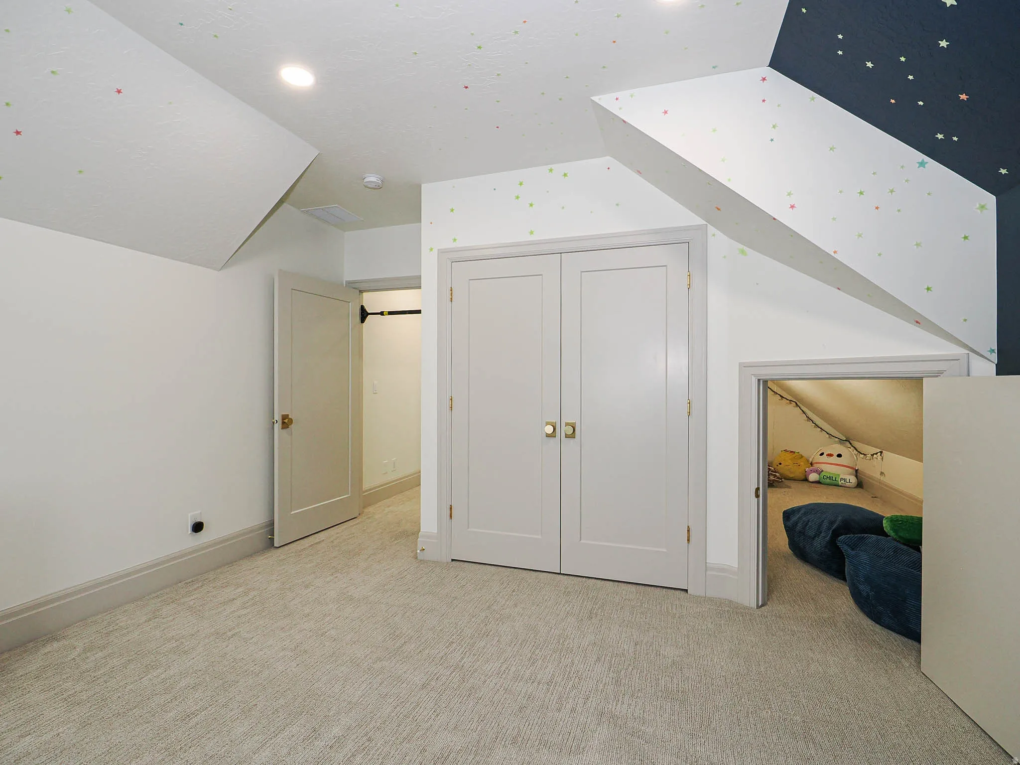Carpeted room featuring a built-in closet with double doors, an open doorway, and a unique alcove with an angled ceiling