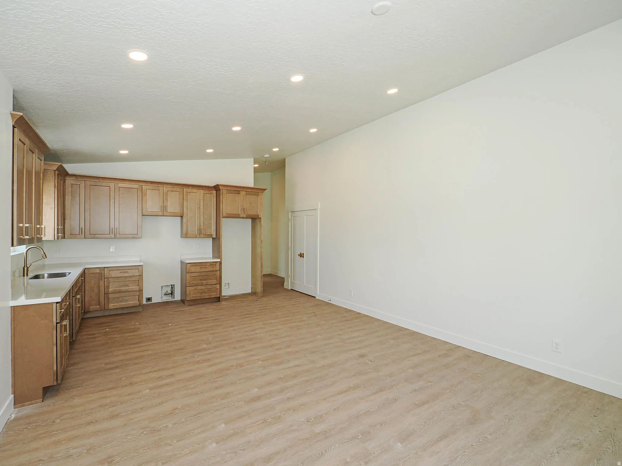 Open-concept living area with light wood-finish flooring, recessed lighting, and a white color palette