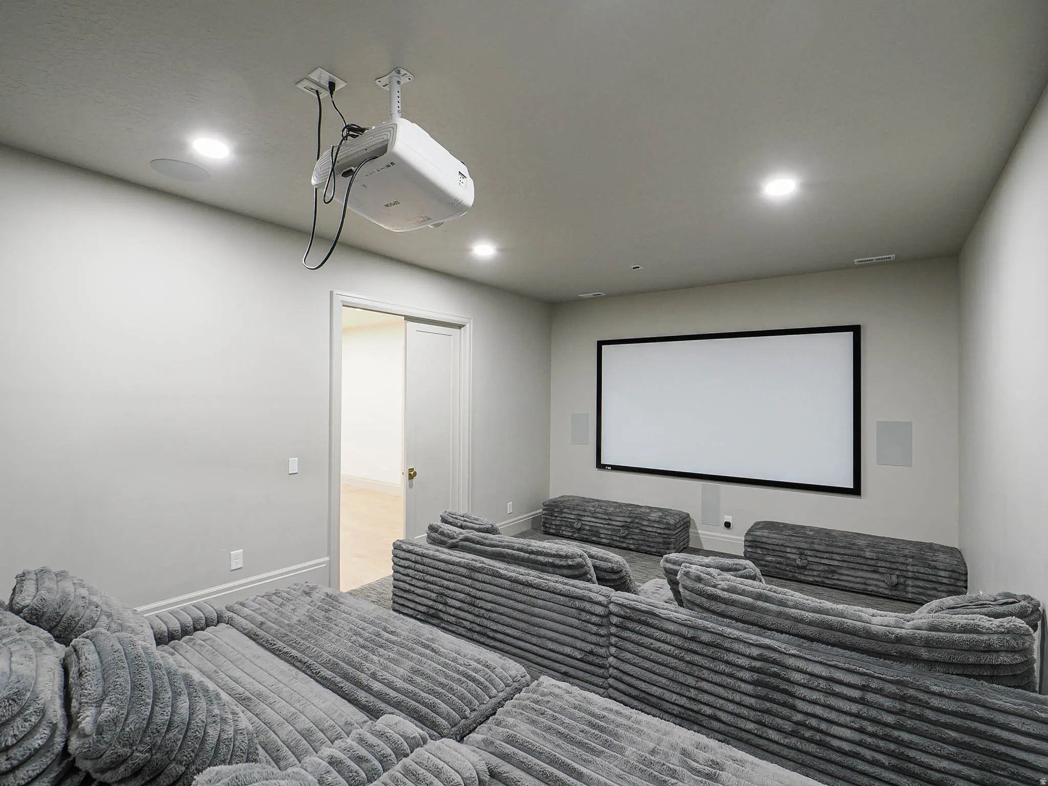 Dedicated media room featuring a large projection screen, ceiling-mounted projector, and integrated wall speakers