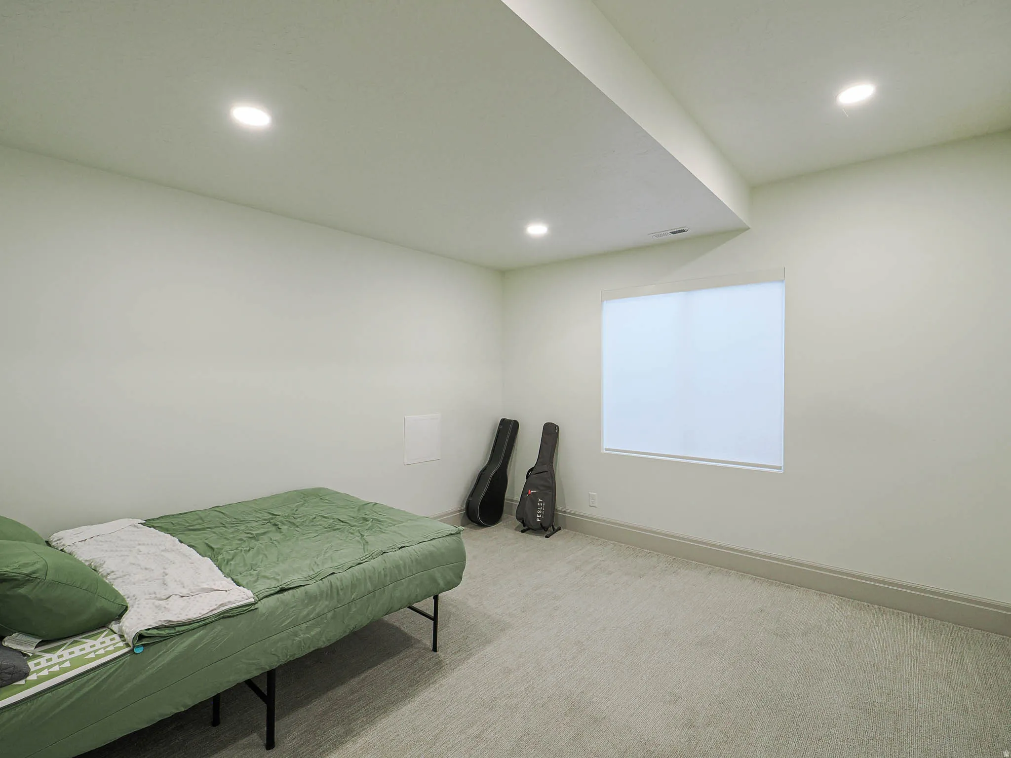 Room featuring light-toned walls, recessed ceiling lighting, and a single window with a roller shade