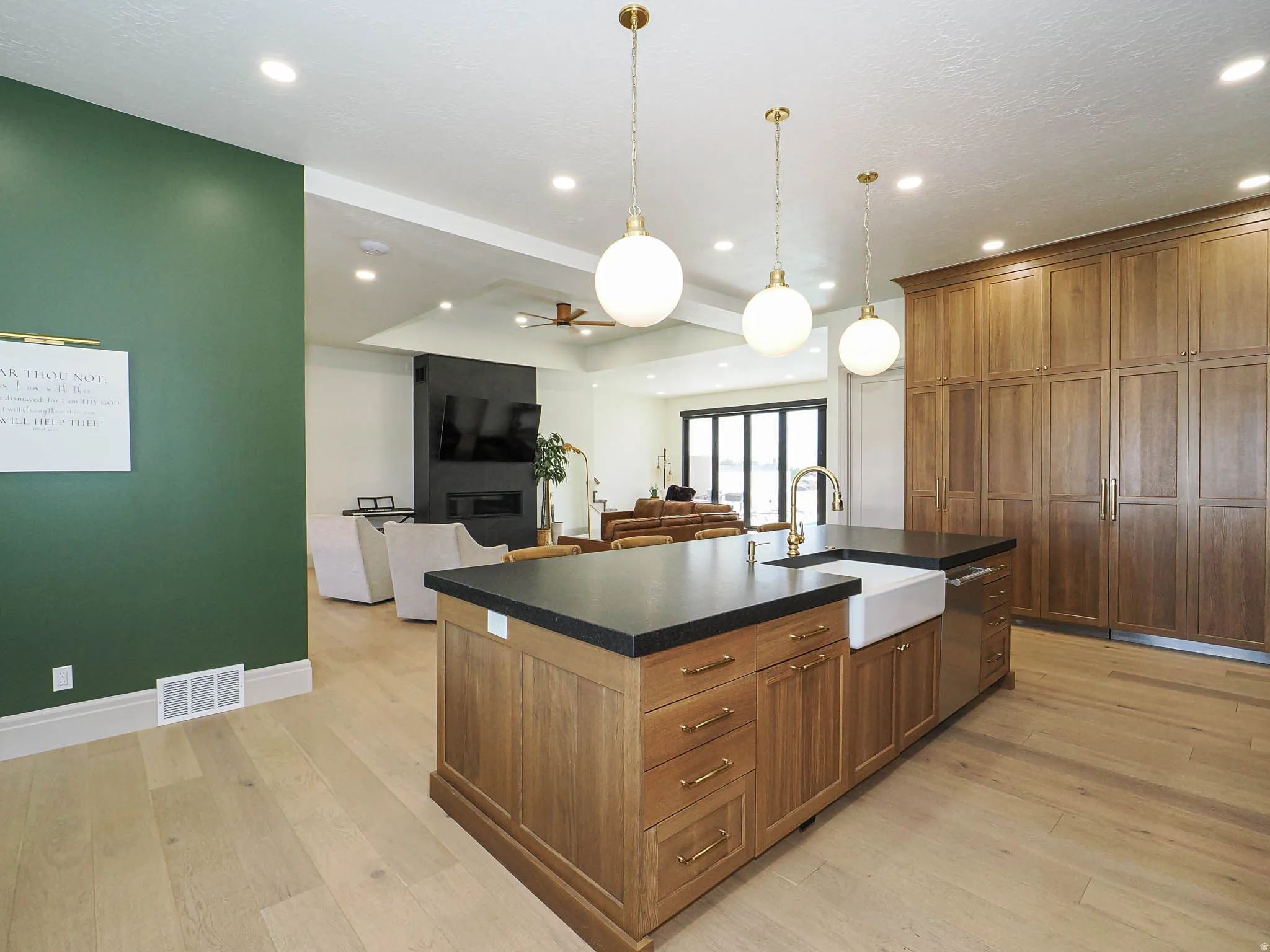 Kitchen island featuring a farmhouse sink, gold-finish faucet, and black countertop