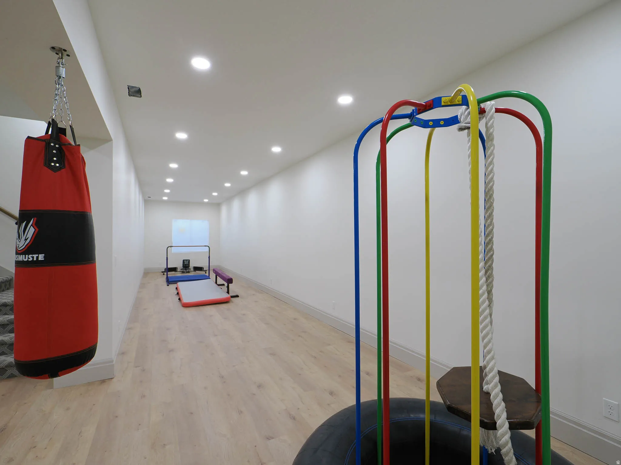 Spacious recreational area featuring wood-finish flooring, recessed lighting, and white baseboards