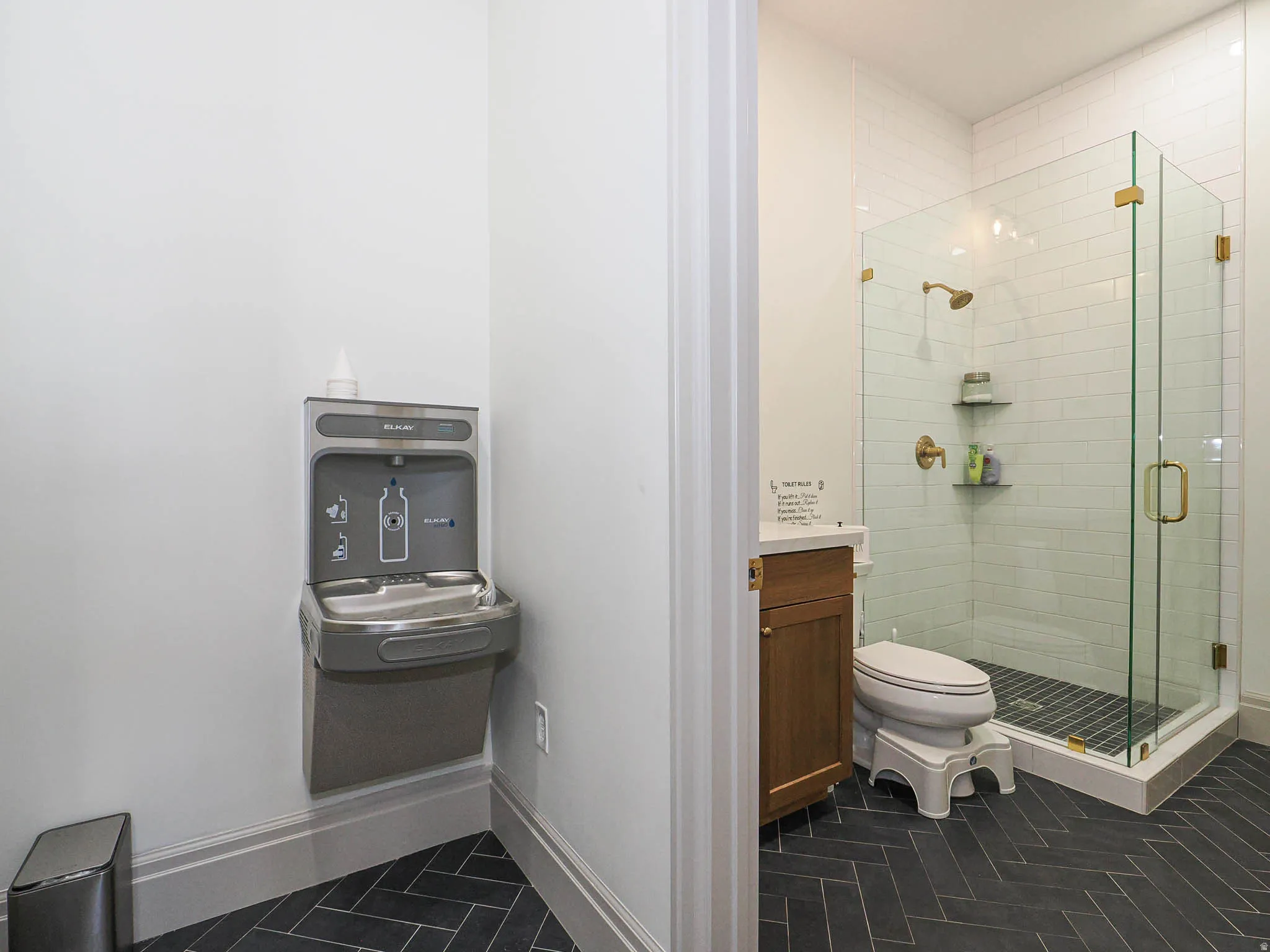 Herringbone tile flooring complementing a clear glass shower enclosure