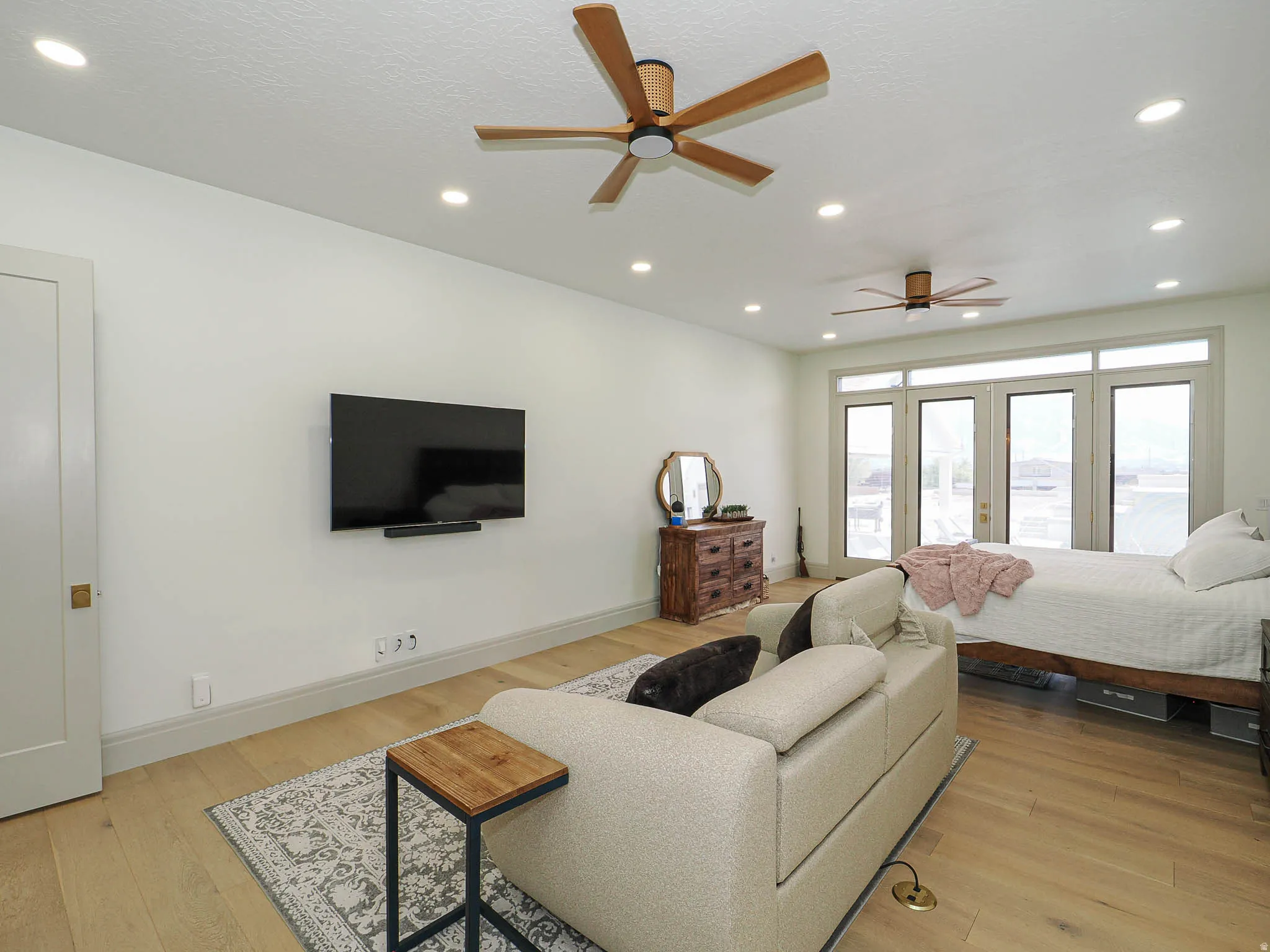 Spacious room featuring wood-finish flooring, recessed lighting, and dual ceiling fans